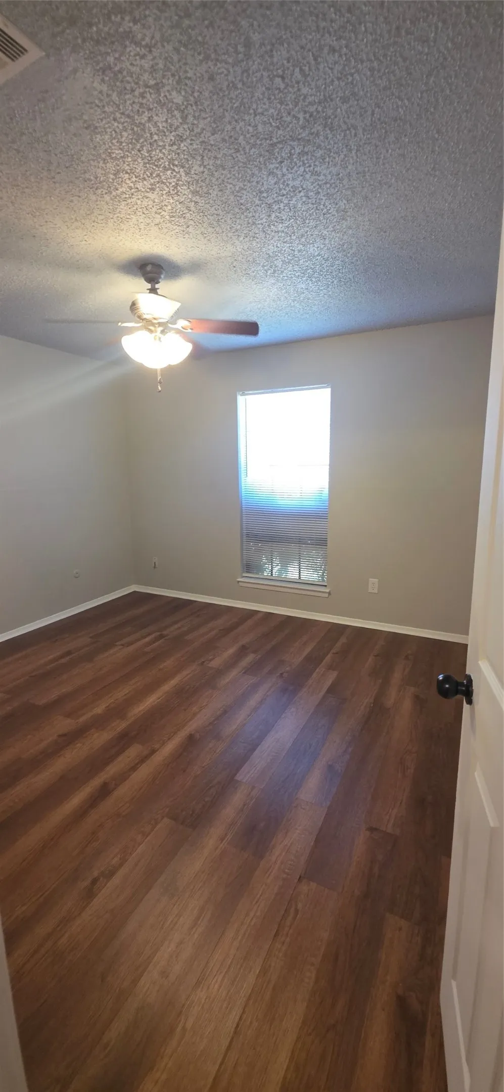 Wood-finish flooring, ceiling fan with integrated lighting, neutral wall paint, and white trim