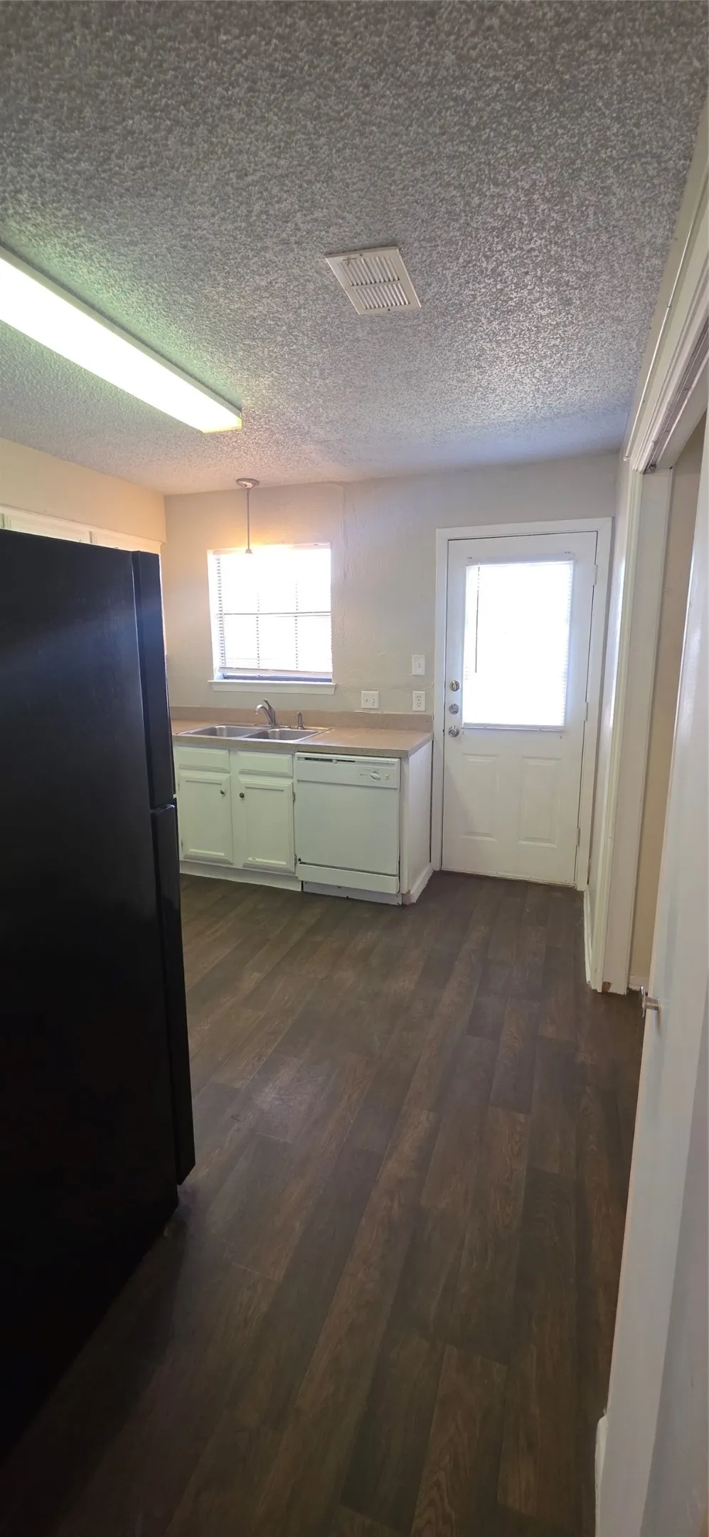 Kitchen featuring wood-finish flooring, white cabinetry, a single basin sink, and a full-light exterior door