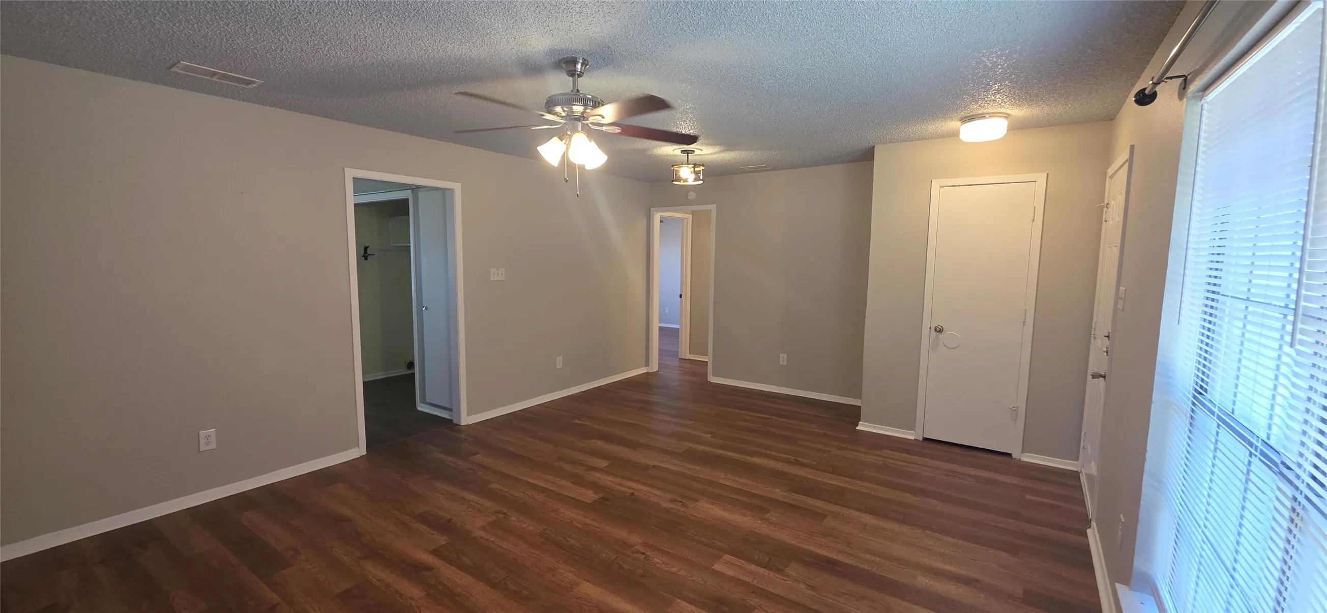 Spacious room with wood-finish flooring, neutral paint, and ceiling fans