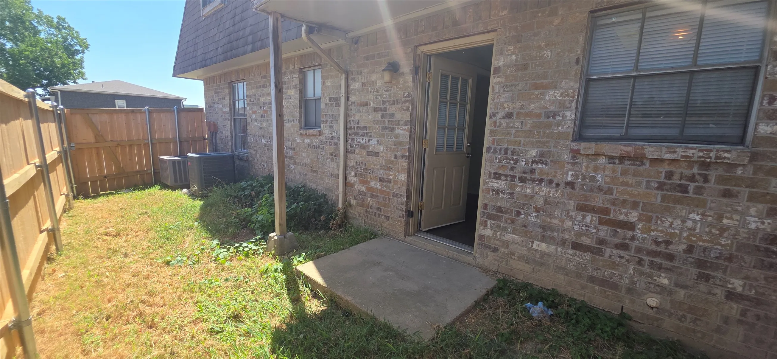 Spacious backyard featuring mature landscaping and a fenced perimeter, with direct access via concrete patio and sliding glass door entry