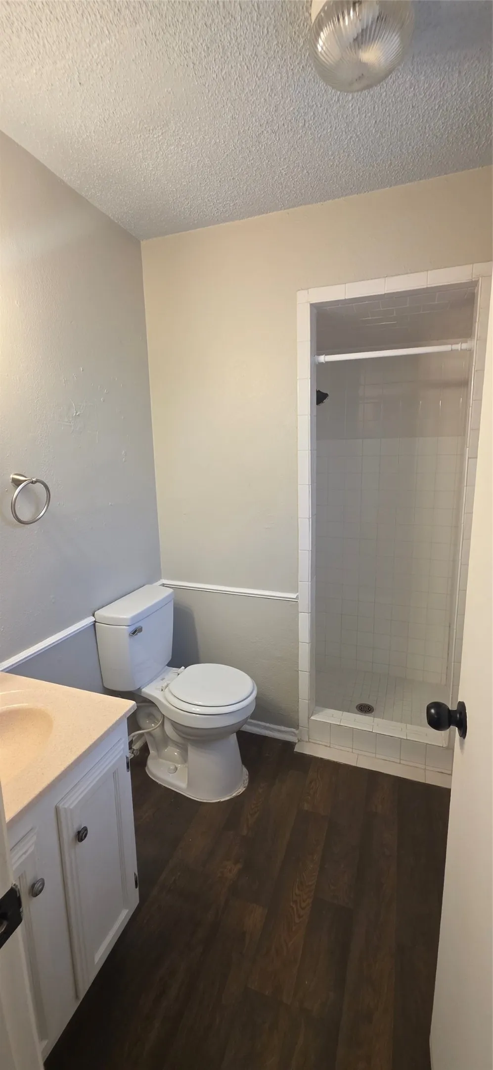 Bathroom featuring a stand-up shower, wood-finish flooring, and a vanity with cabinet storage