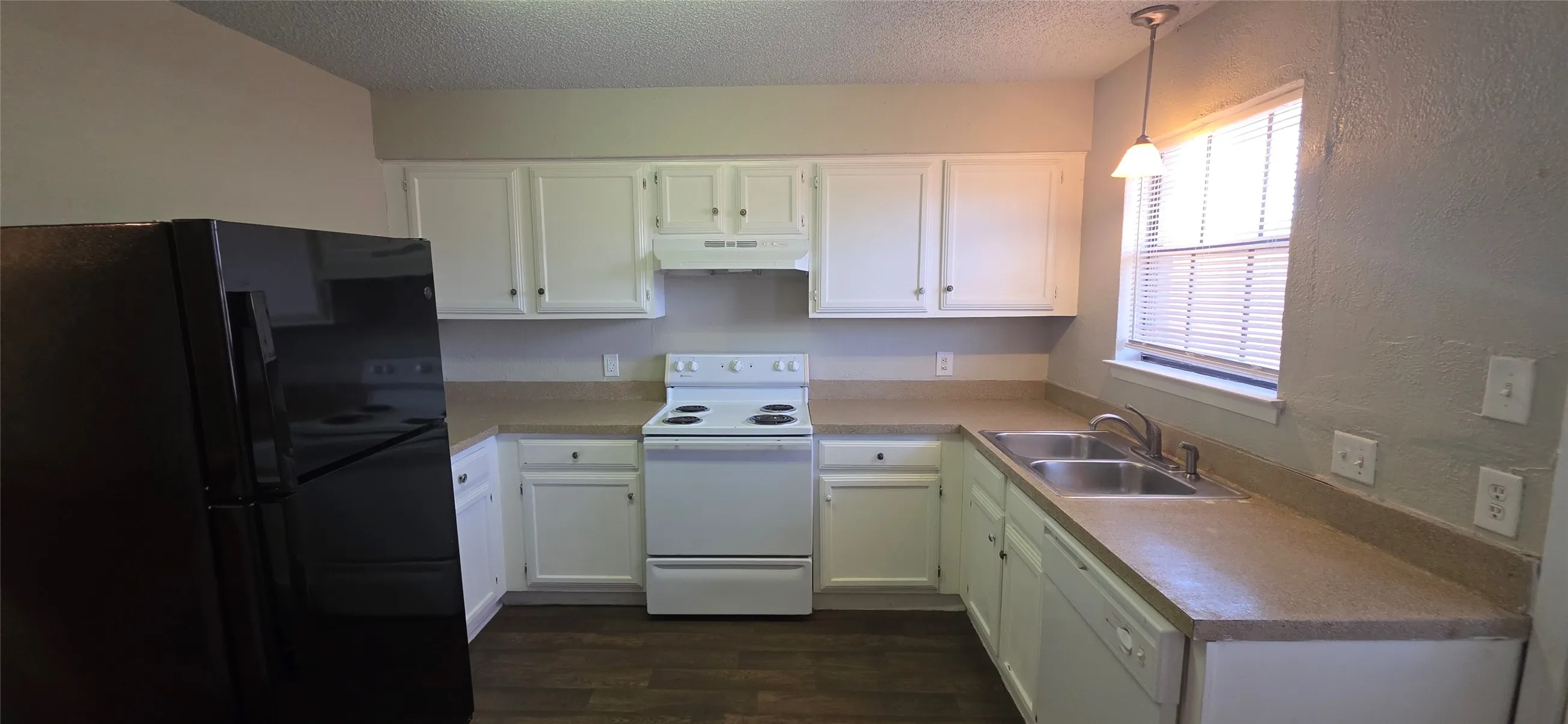 Kitchen featuring white cabinetry, light-toned countertops, a stainless steel double sink, white range, and wood-finish flooring