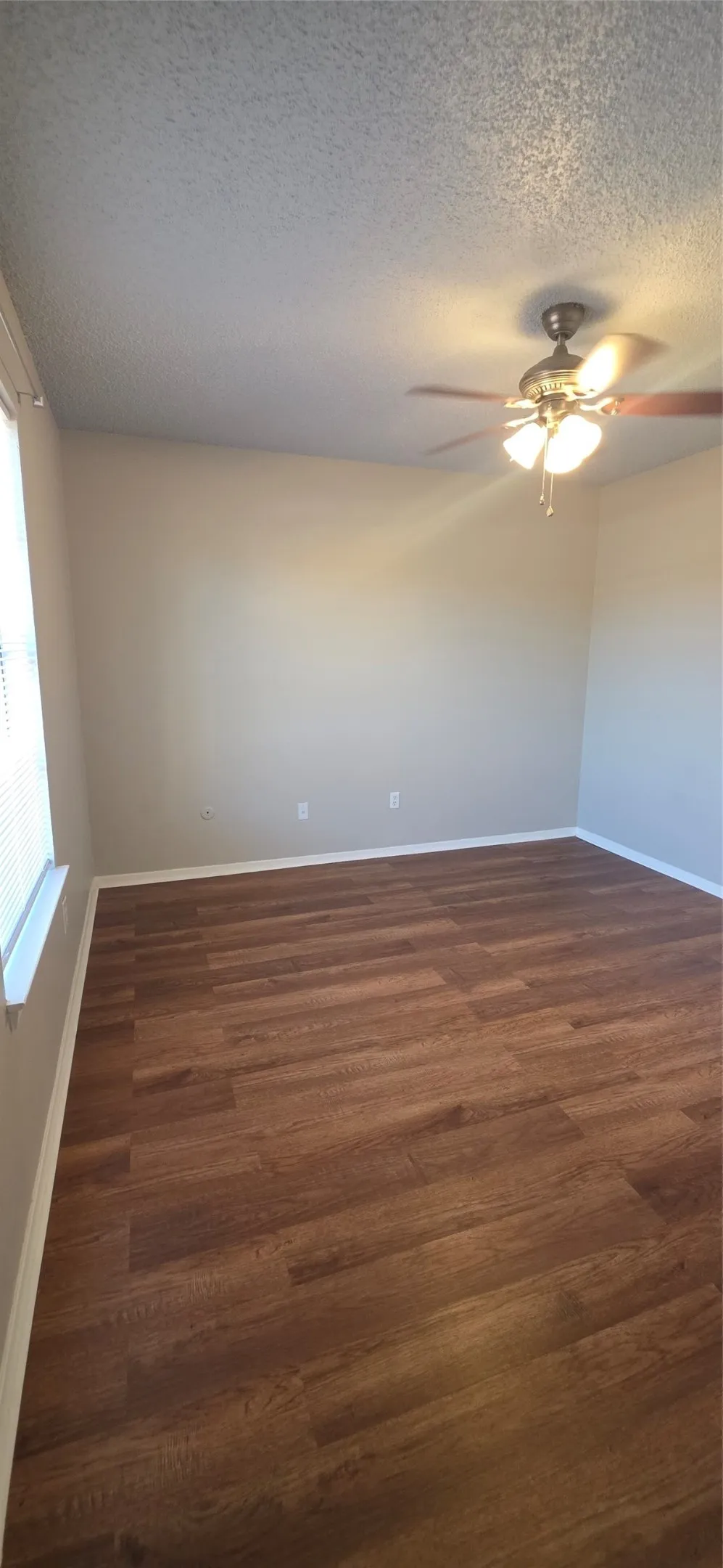 Wood-finish flooring, neutral-toned walls, and a ceiling fan with integrated lighting