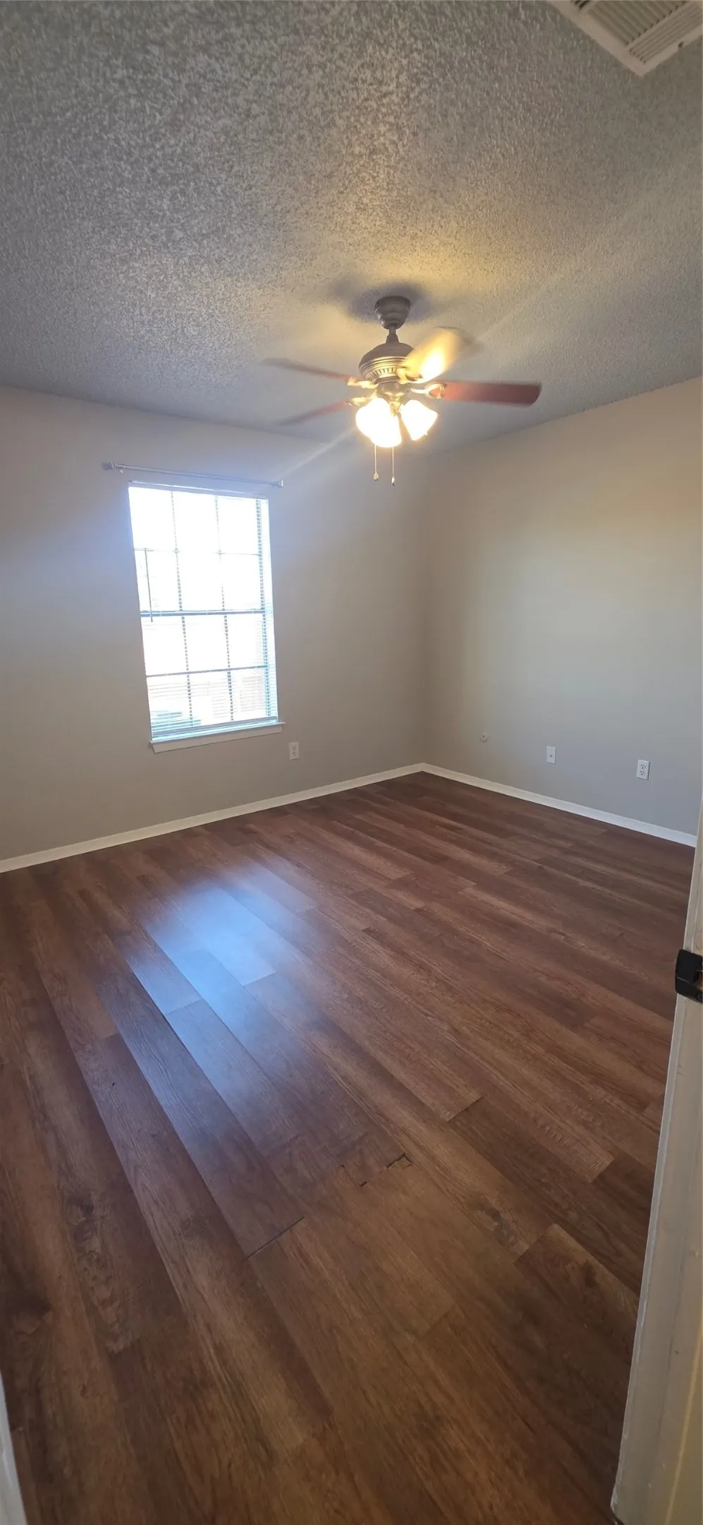 Wood-finish flooring, ceiling fan with integrated lighting, and a multi-pane window