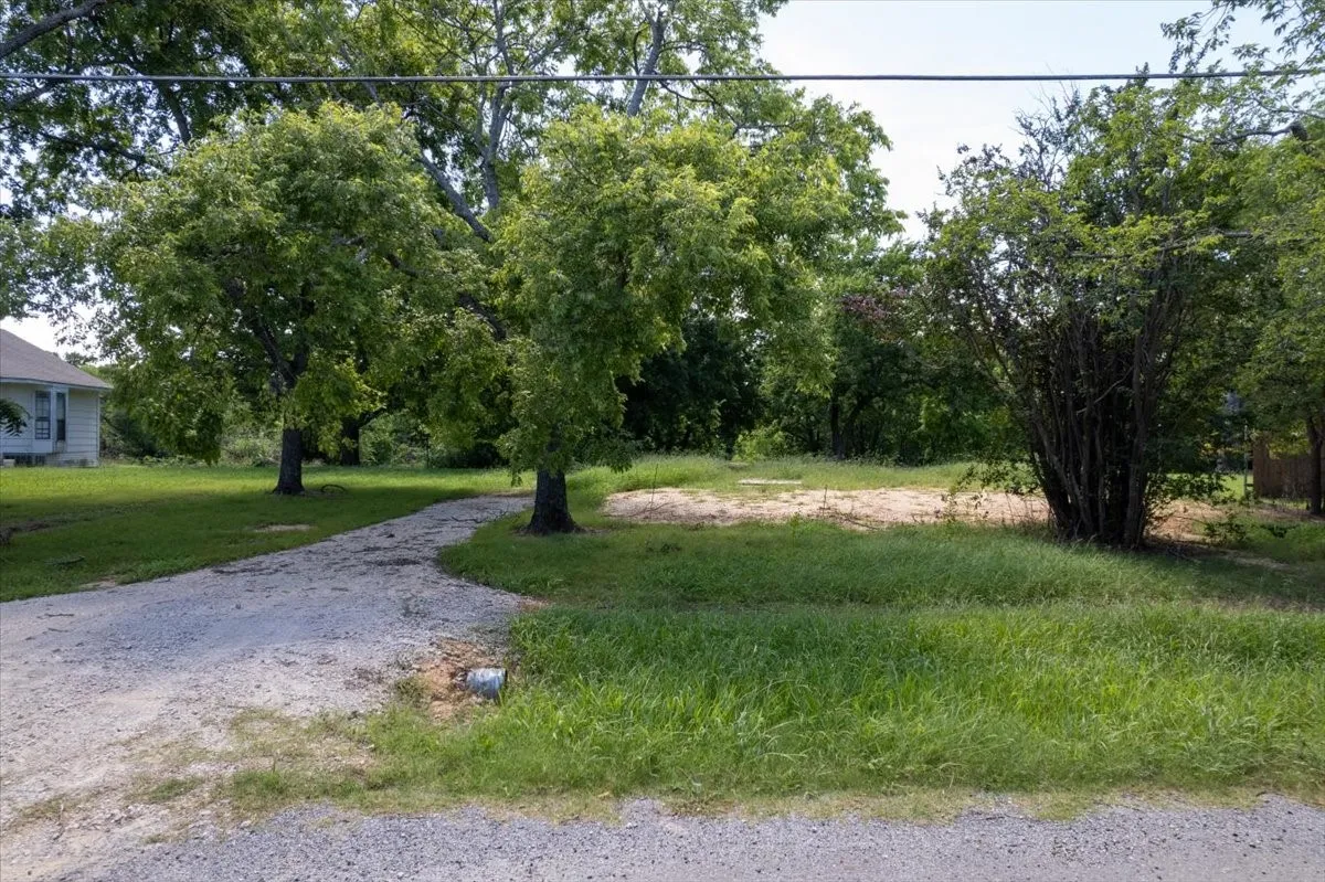 Gravel driveway entrance — shaded lot access