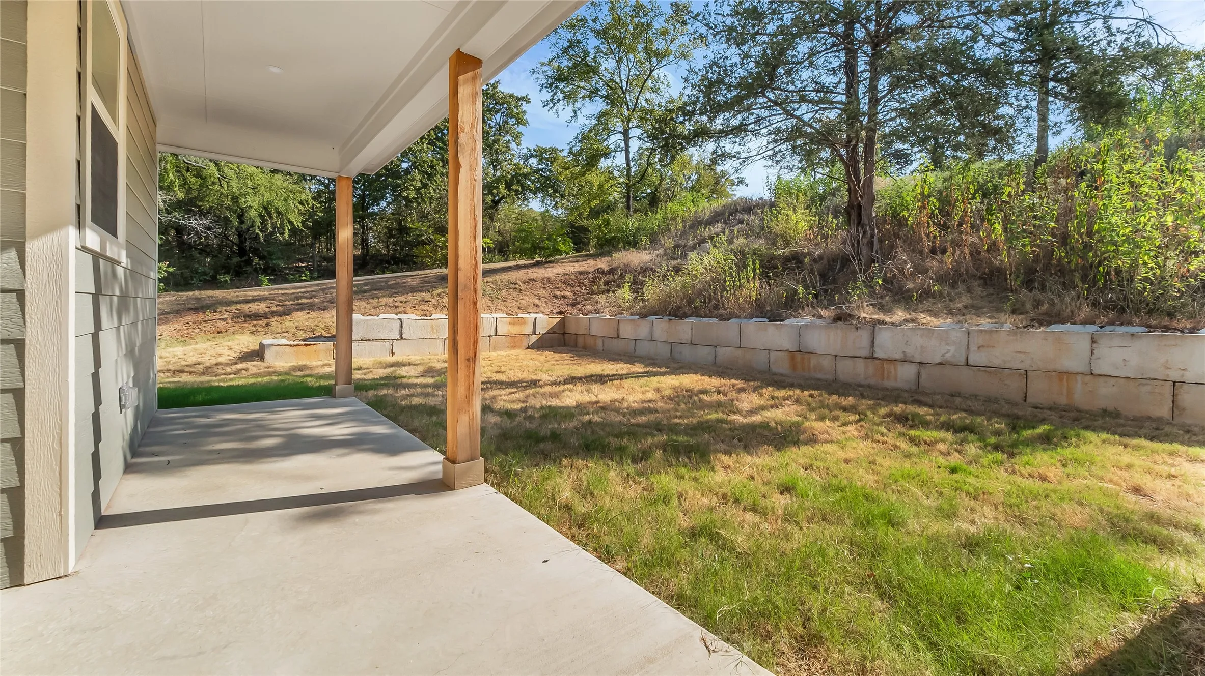 Covered patio with concrete flooring, wood posts, and horizontal siding