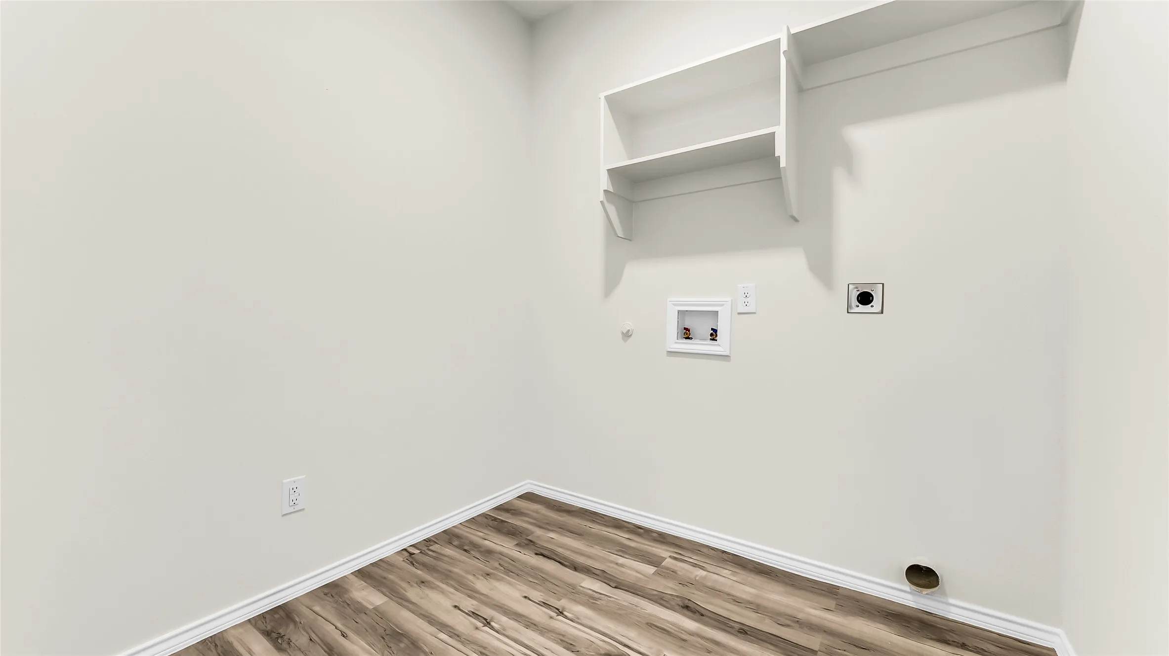 Dedicated laundry area featuring wood-finish flooring, light-toned walls, and built-in shelving