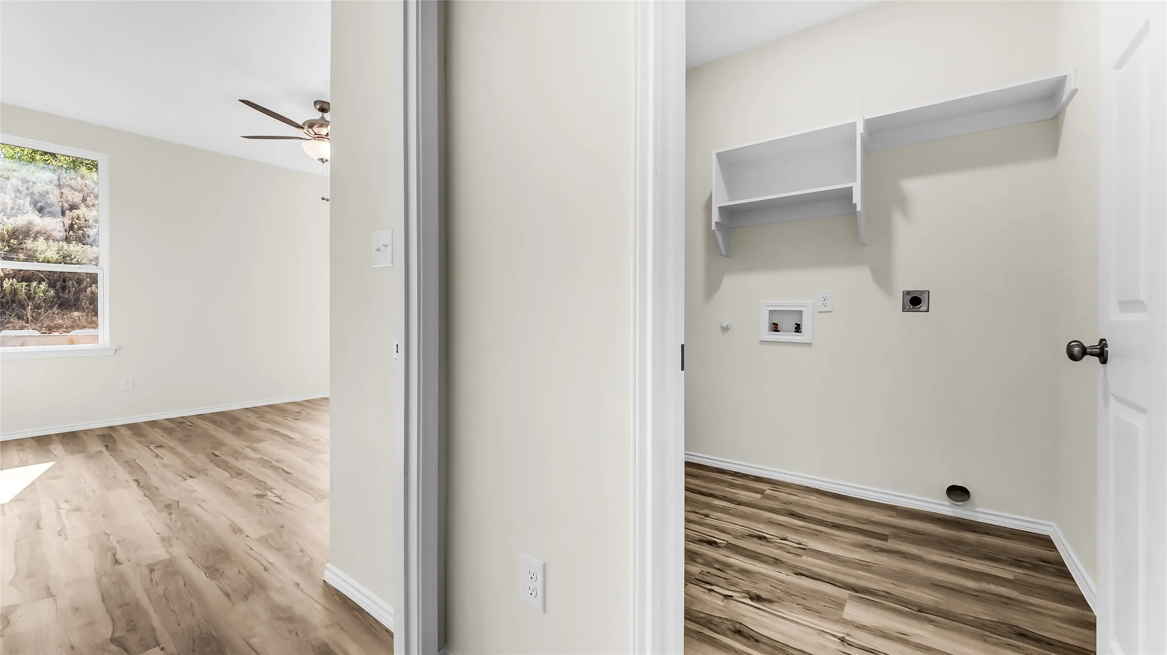 Dedicated laundry area with built-in shelving, wood-finish flooring, and white walls
