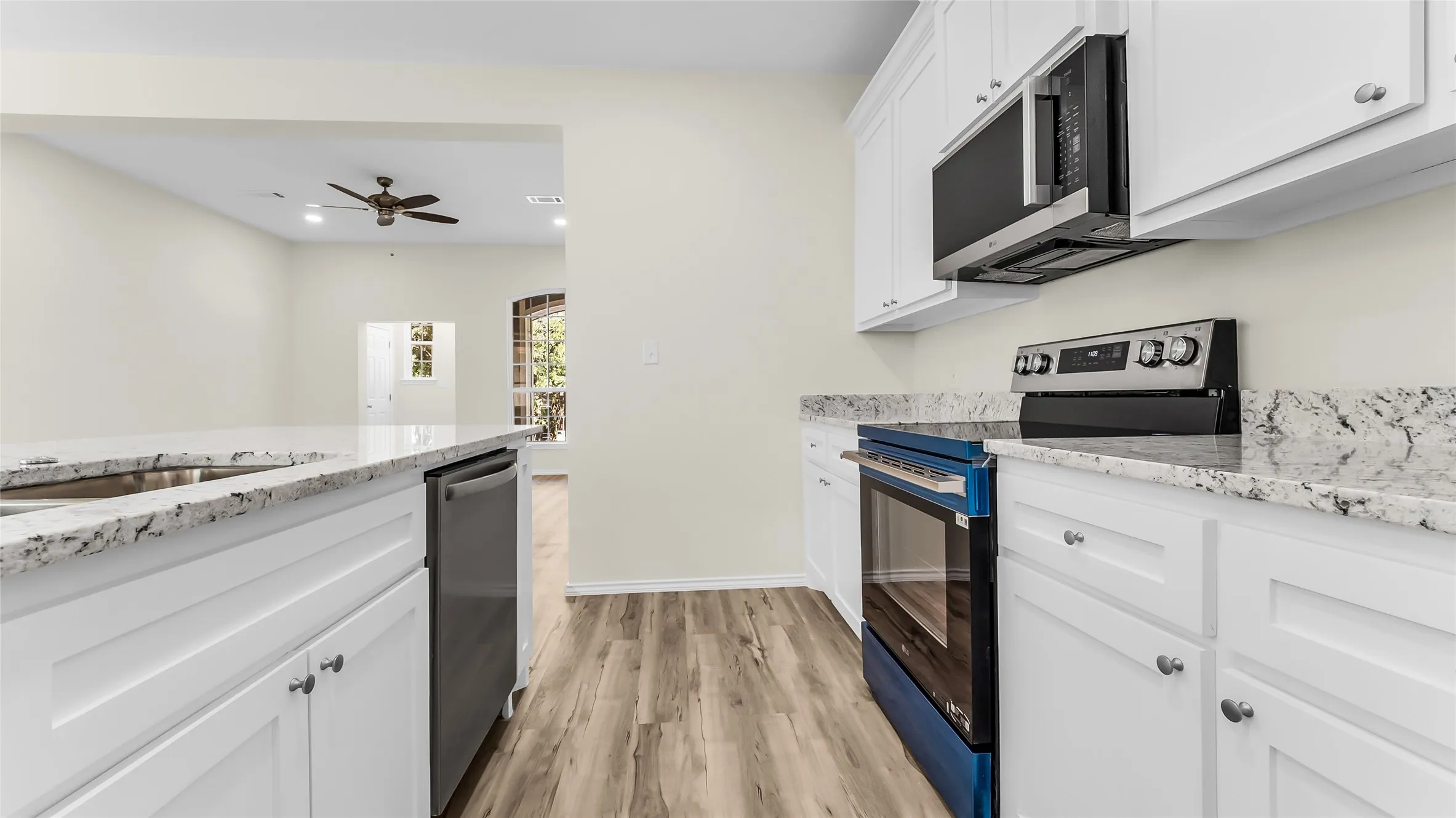 Kitchen featuring white cabinetry, stone countertops, stainless steel appliances, and wood-finish flooring