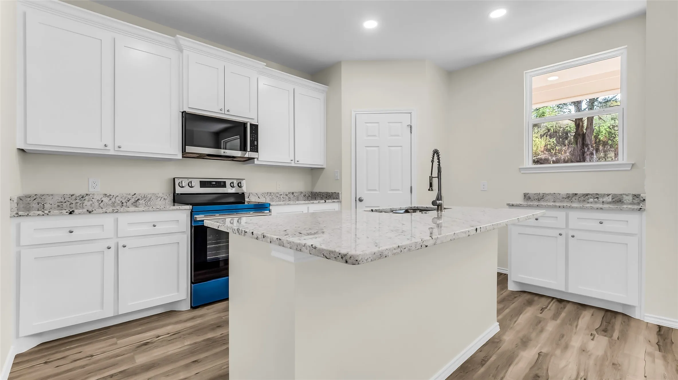 Kitchen featuring white cabinetry, granite countertops, an undermount sink with a matte black faucet, stainless steel appliances, and wood-finish flooring