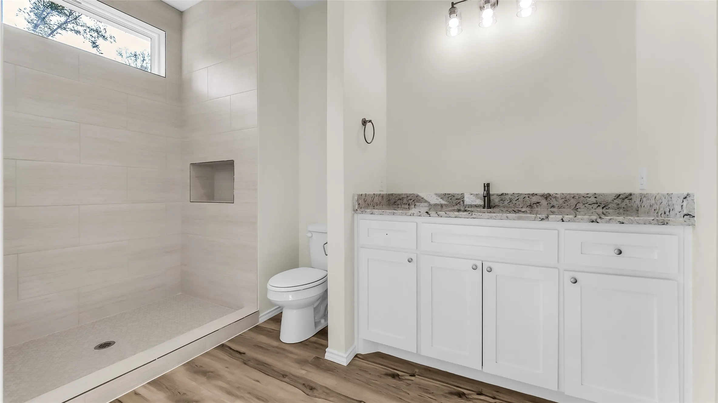 Walk-in shower with tiled walls and an inset niche, complete with a transom window