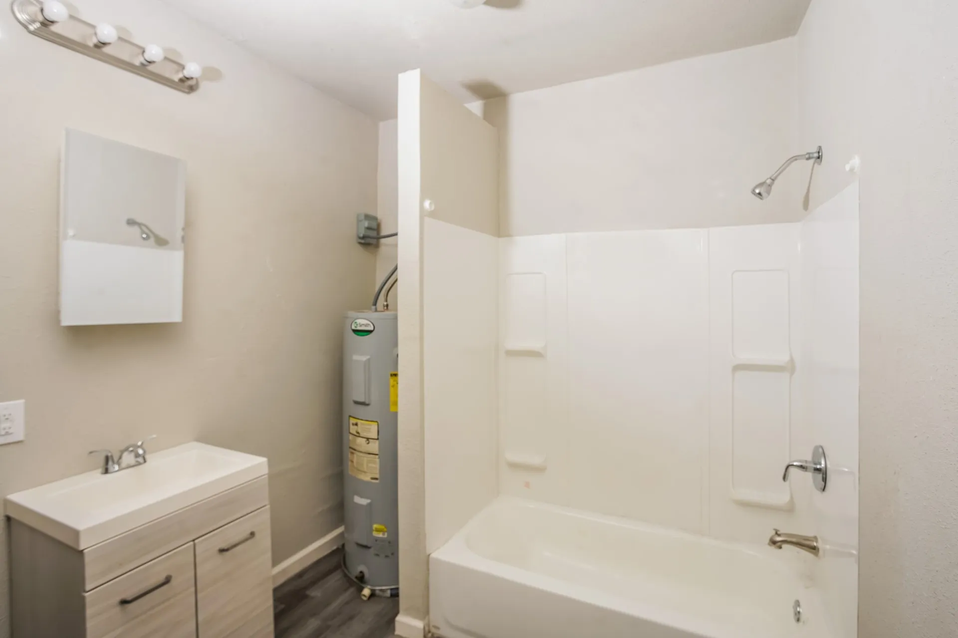 Bathroom featuring a bathtub with shower, single vanity, and wood-finish flooring