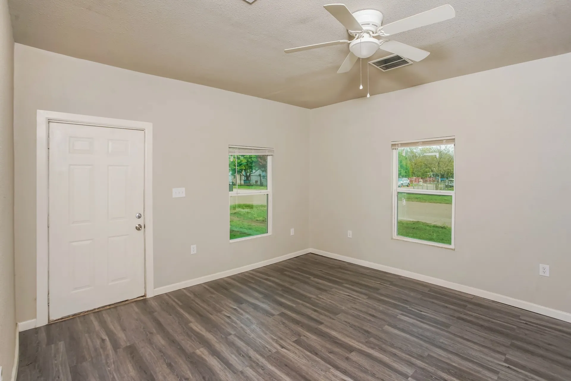 Interior room featuring wood-finish flooring, two windows, and a ceiling fan