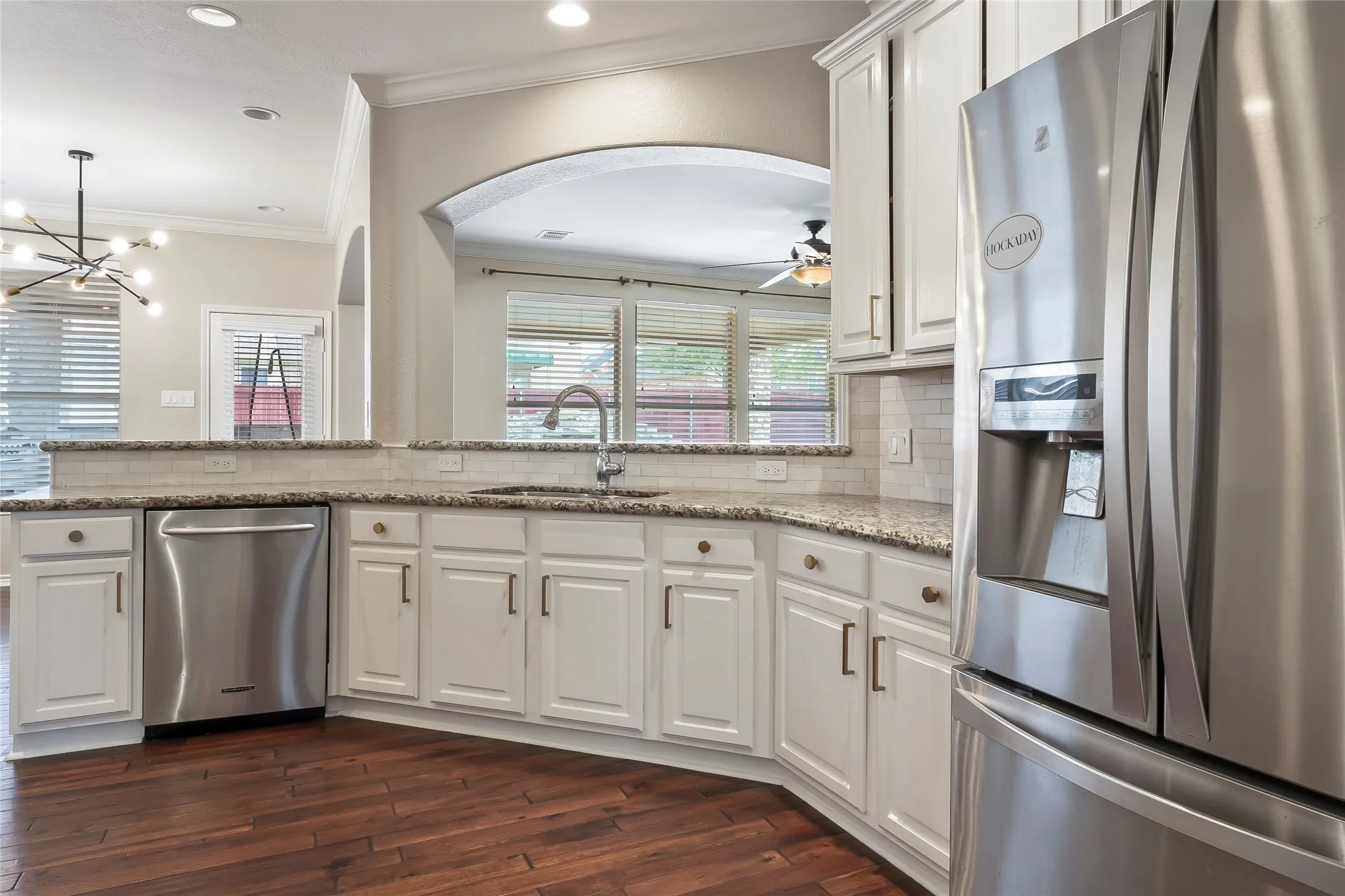 Kitchen featuring white cabinetry, stainless steel appliances, granite countertops, tile backsplash, and wood-finish flooring
