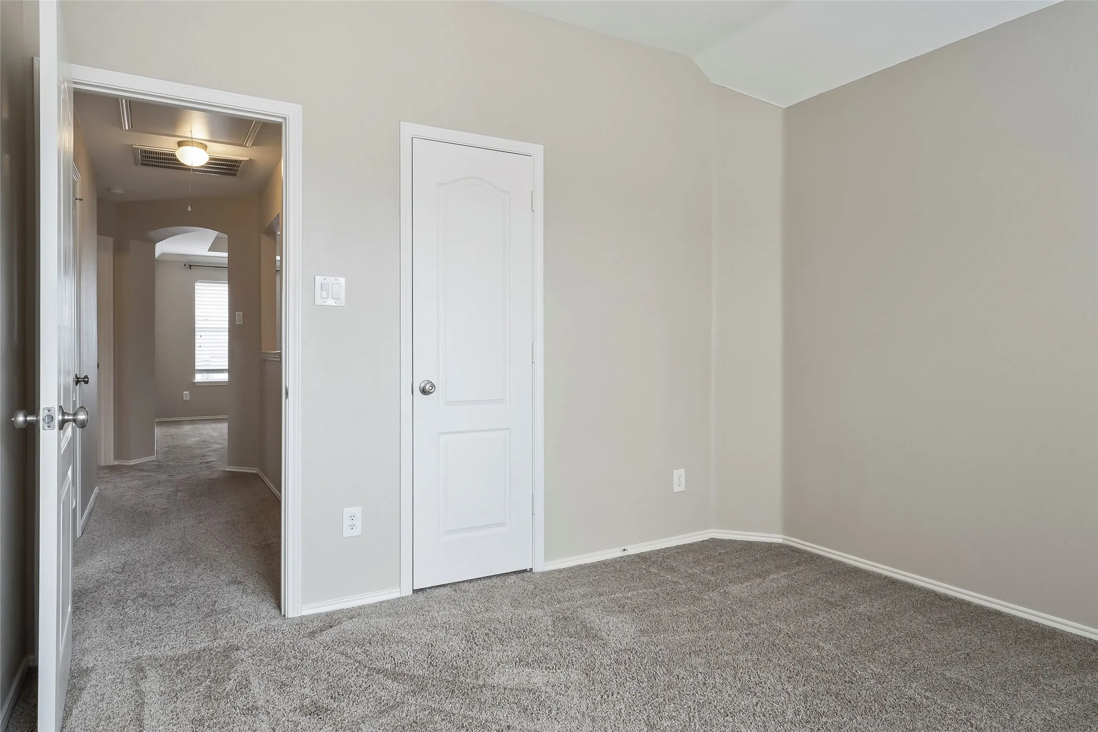 Carpeted room with neutral wall tones and a vaulted ceiling