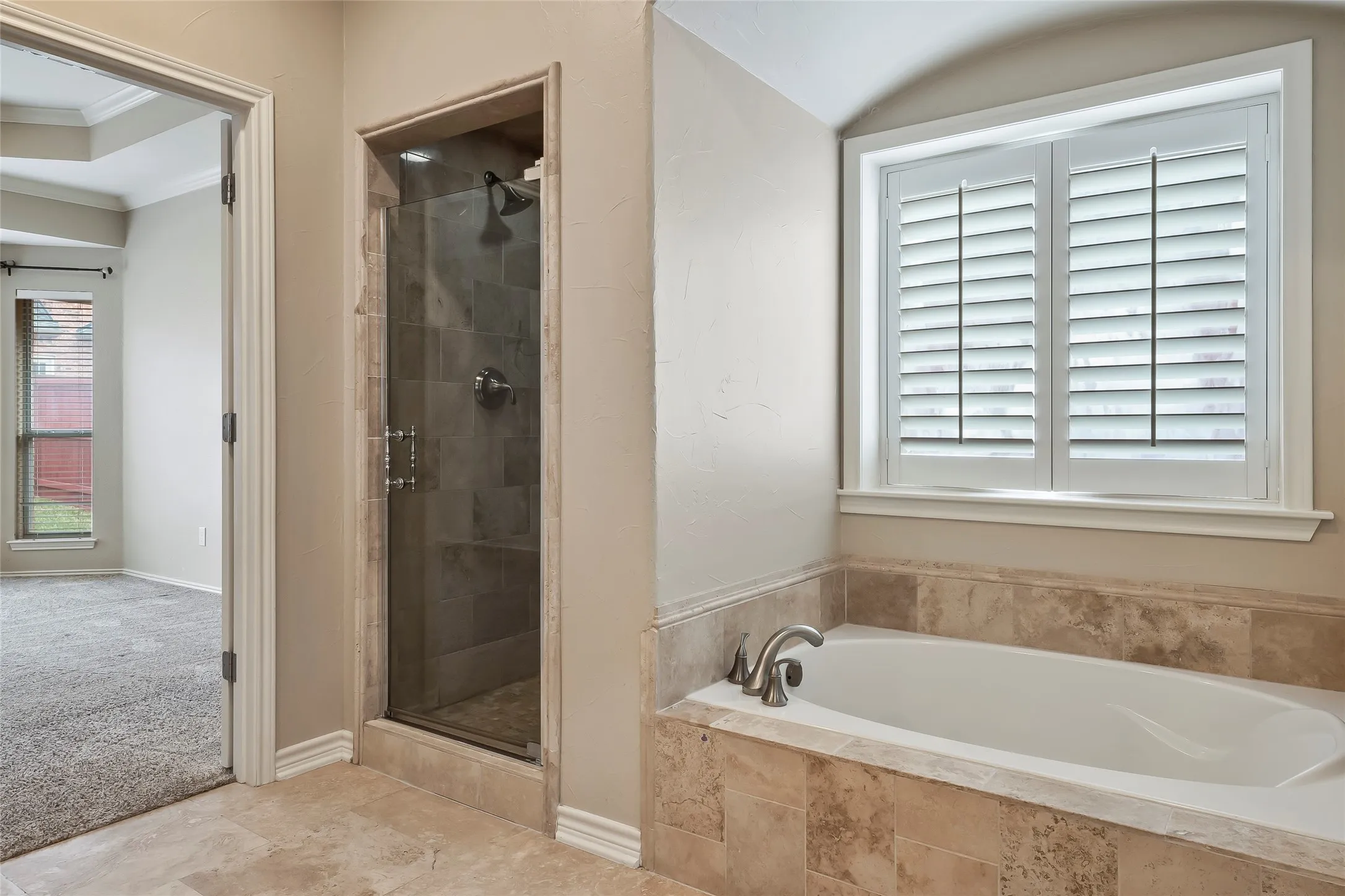 Integrated soaking tub with stone tile surround and plantation shutters