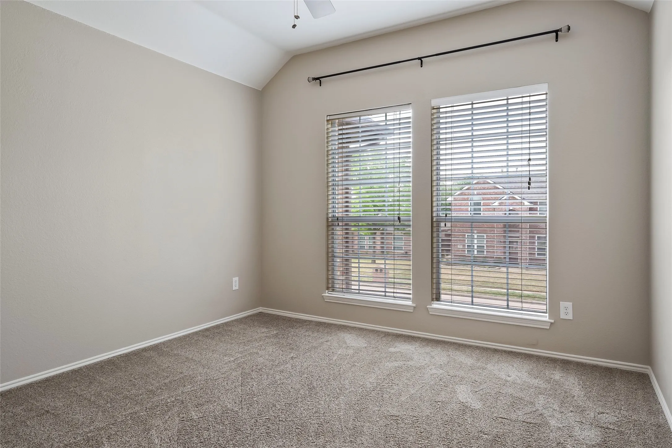 Carpeted room with vaulted ceiling and a ceiling fan
