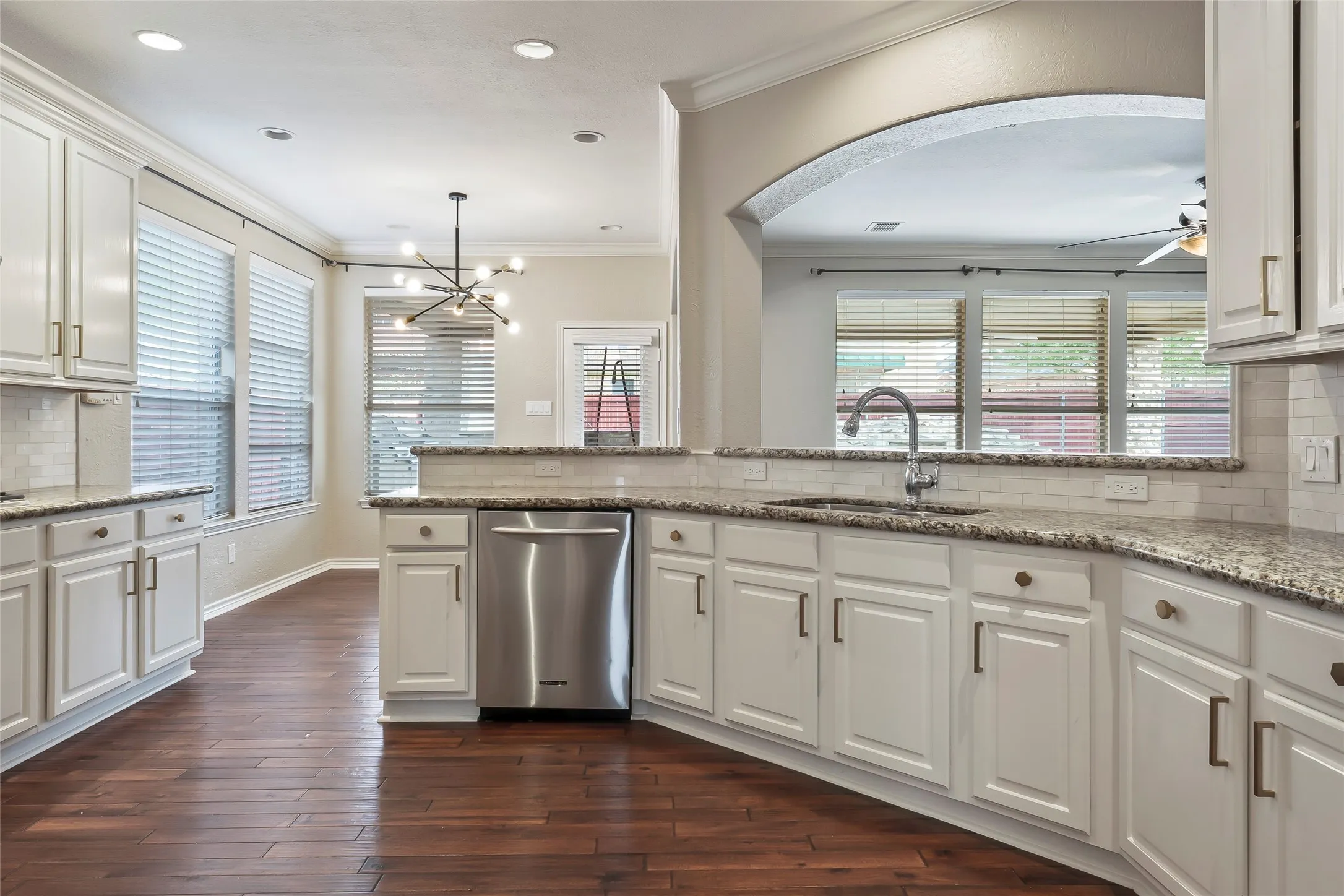 Kitchen featuring white cabinetry, granite countertops, a stainless steel dishwasher, an undermount sink with a gooseneck faucet, and wood-finish flooring