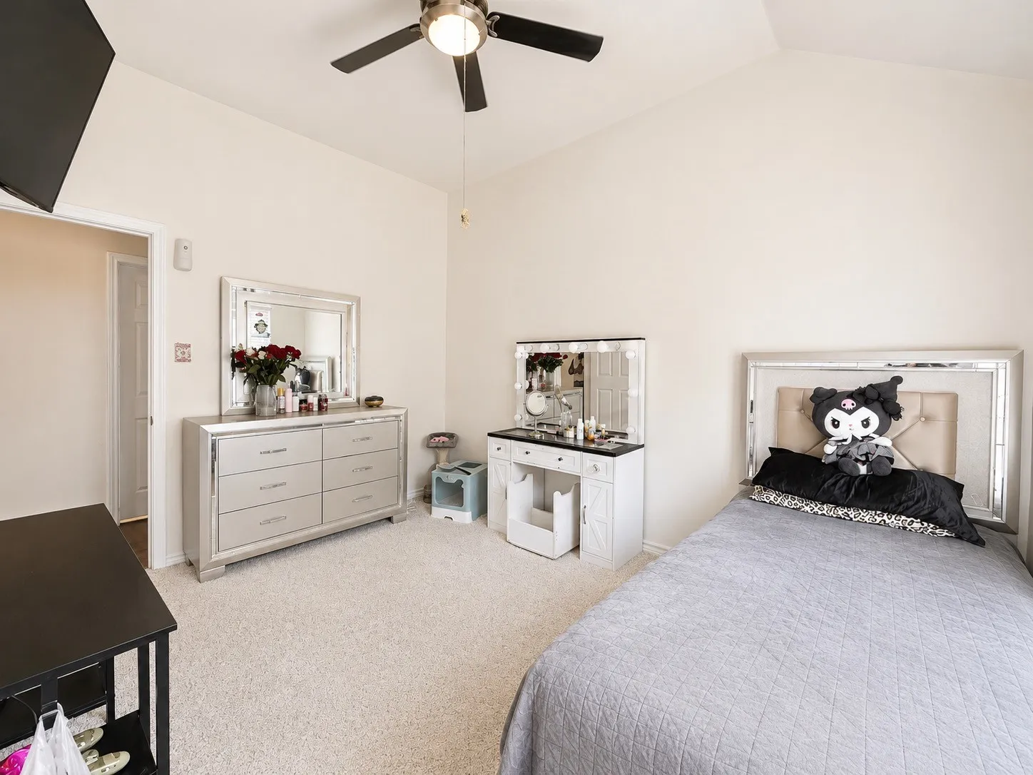Spacious bedroom featuring neutral carpeting, a ceiling fan with integrated lighting, and a large window with custom built-in cabinetry