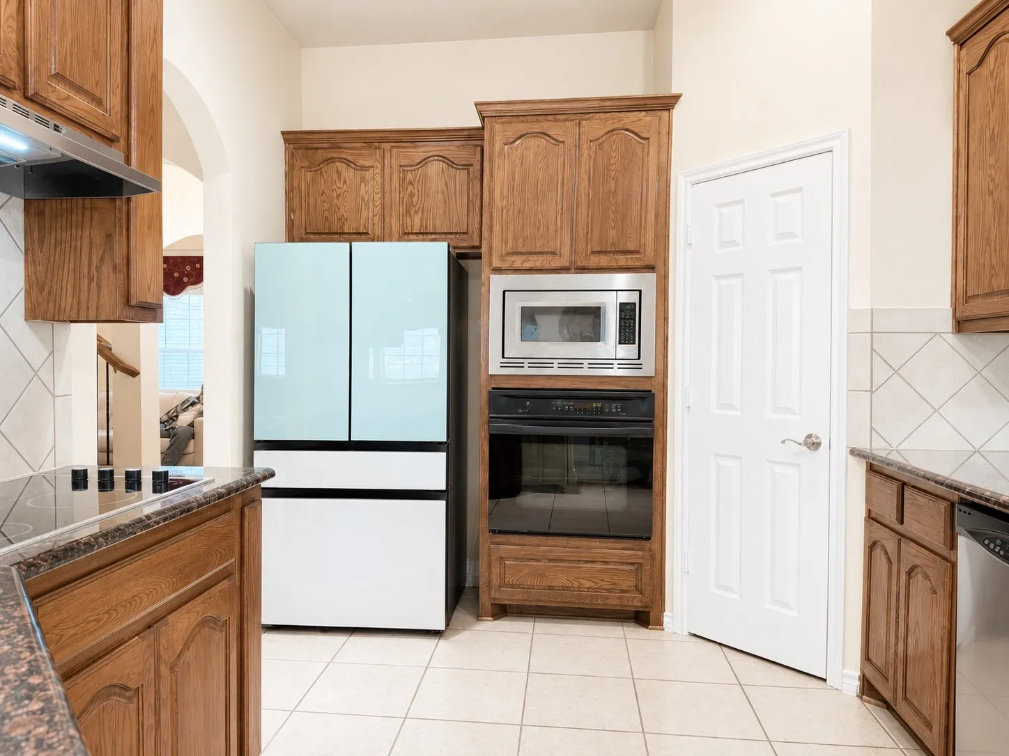 Wood-finish cabinetry, tile flooring, built-in oven, built-in microwave, and tile backsplash