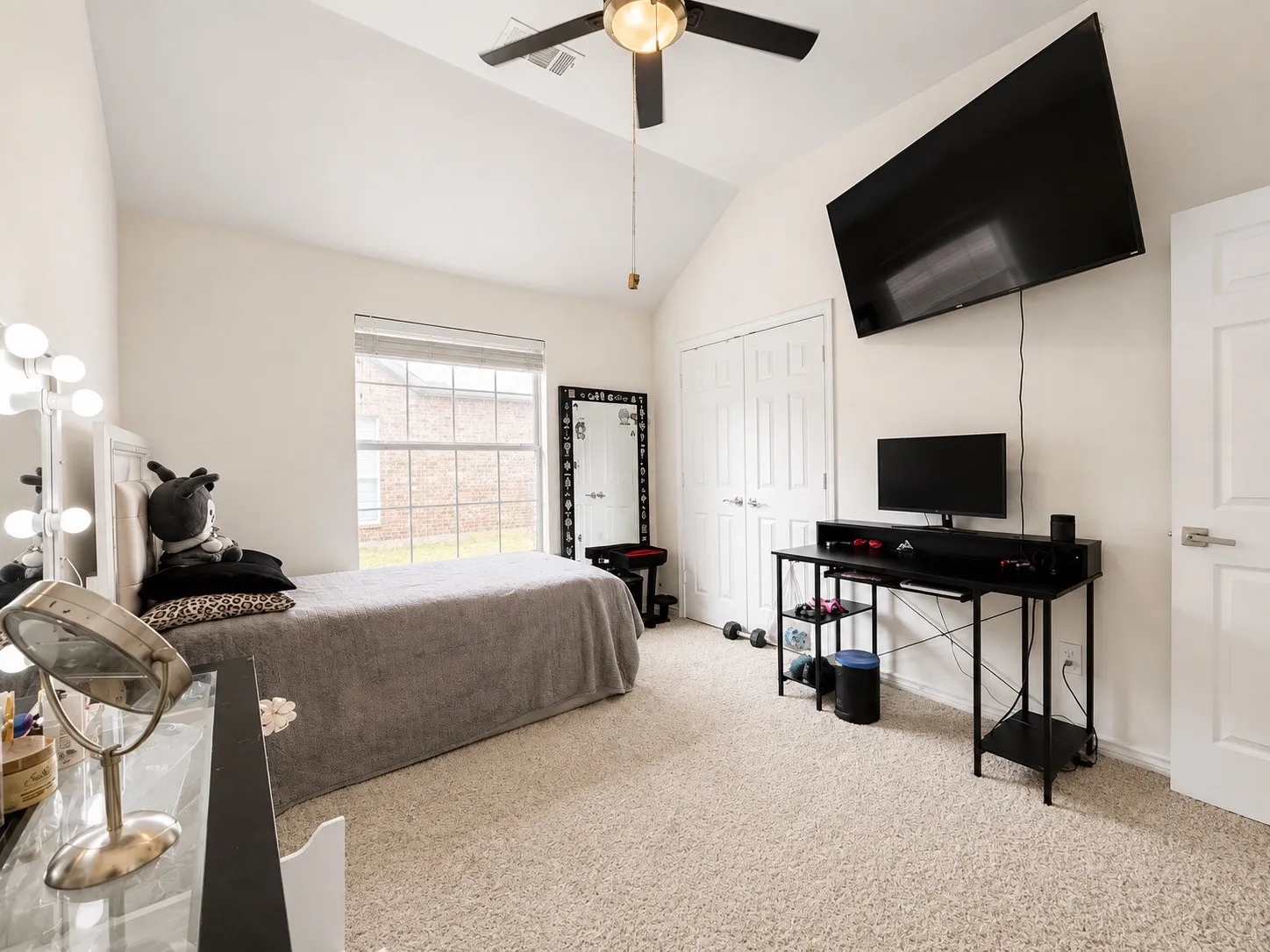 Vaulted ceiling with an attached ceiling fan, double-door closet, and carpeted flooring