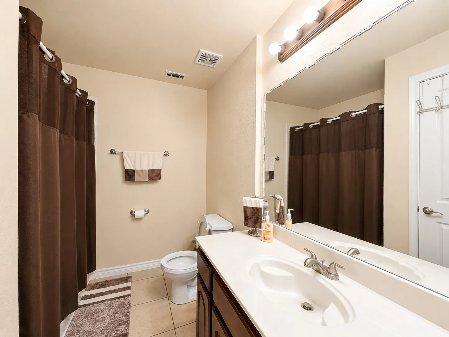 Spa-inspired primary bathroom featuring a generous vanity with dual sinks, polished chrome fixtures, and ample countertop space
