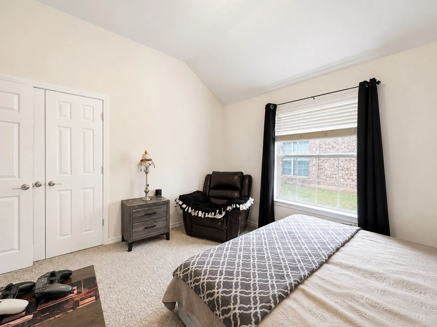 Neutral wall finishes, vaulted ceiling, and carpeted flooring
