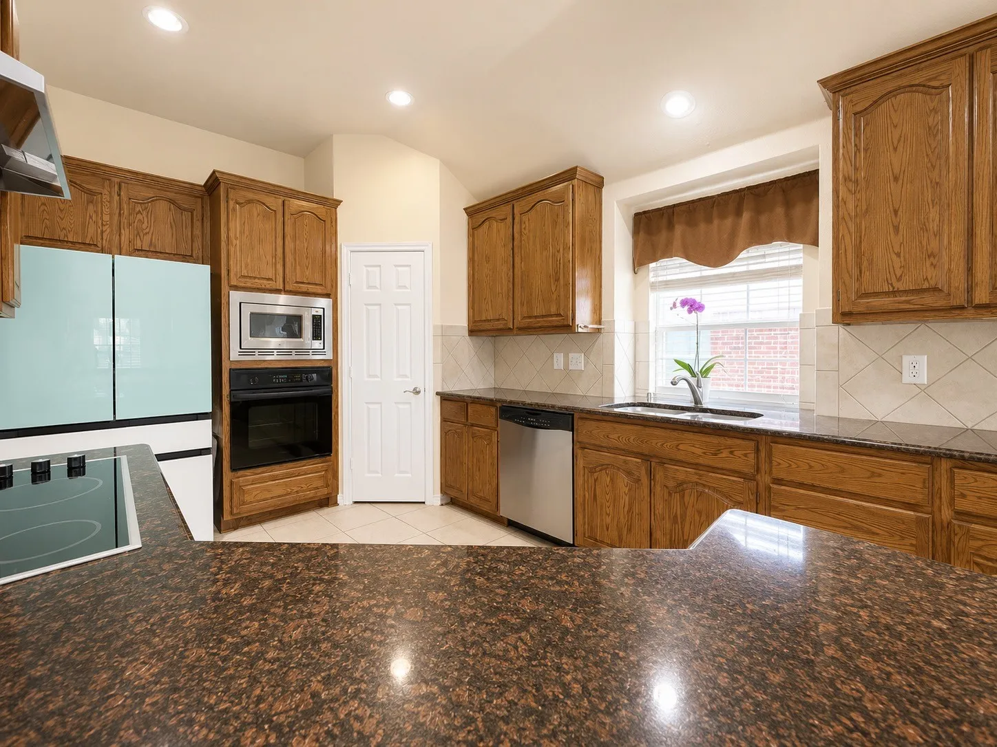 Kitchen featuring extensive cabinetry, built-in microwave, wall oven, cooktop, and a stainless steel dishwasher