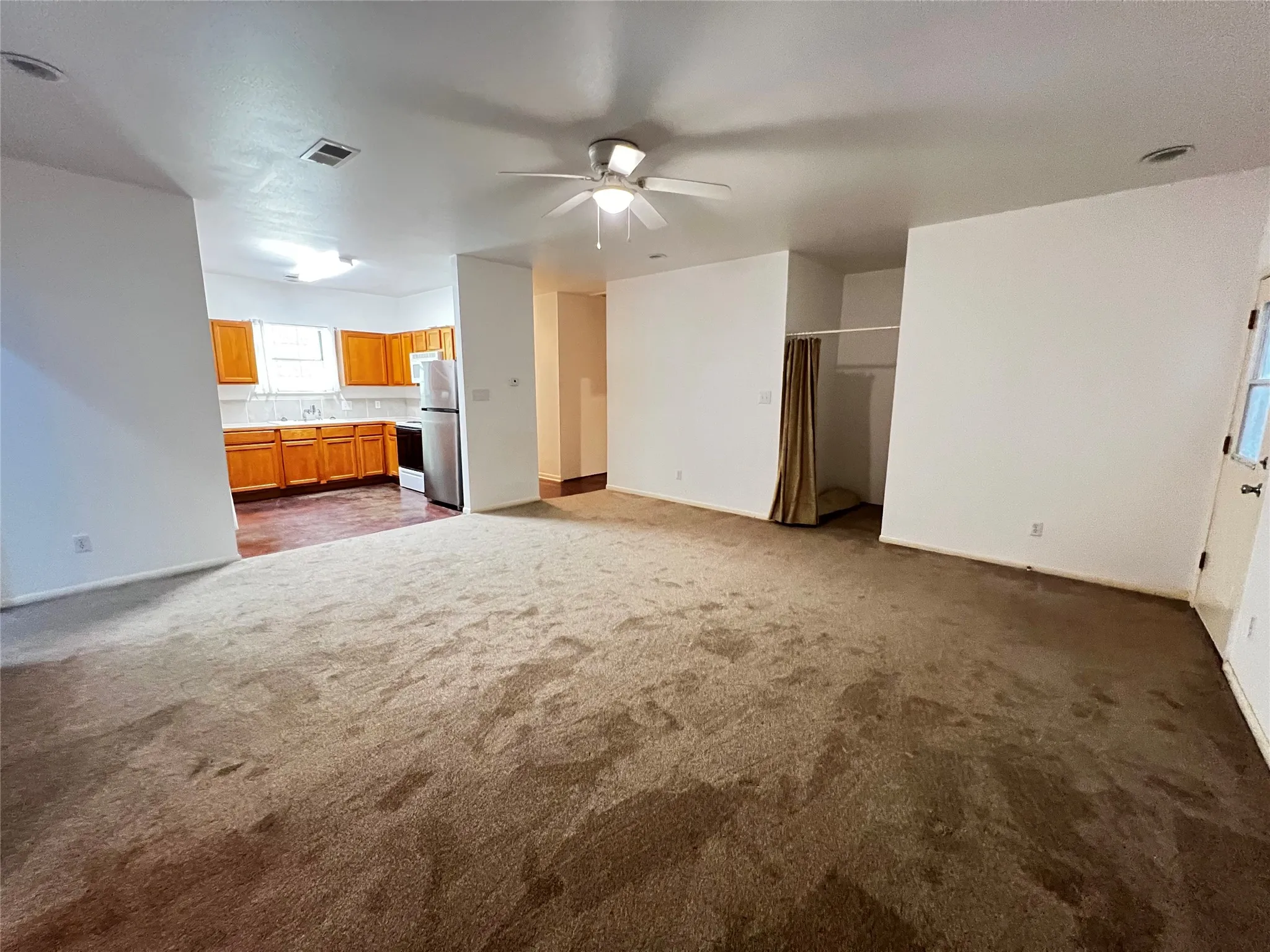 Open-concept living area with carpet flooring and a ceiling fan