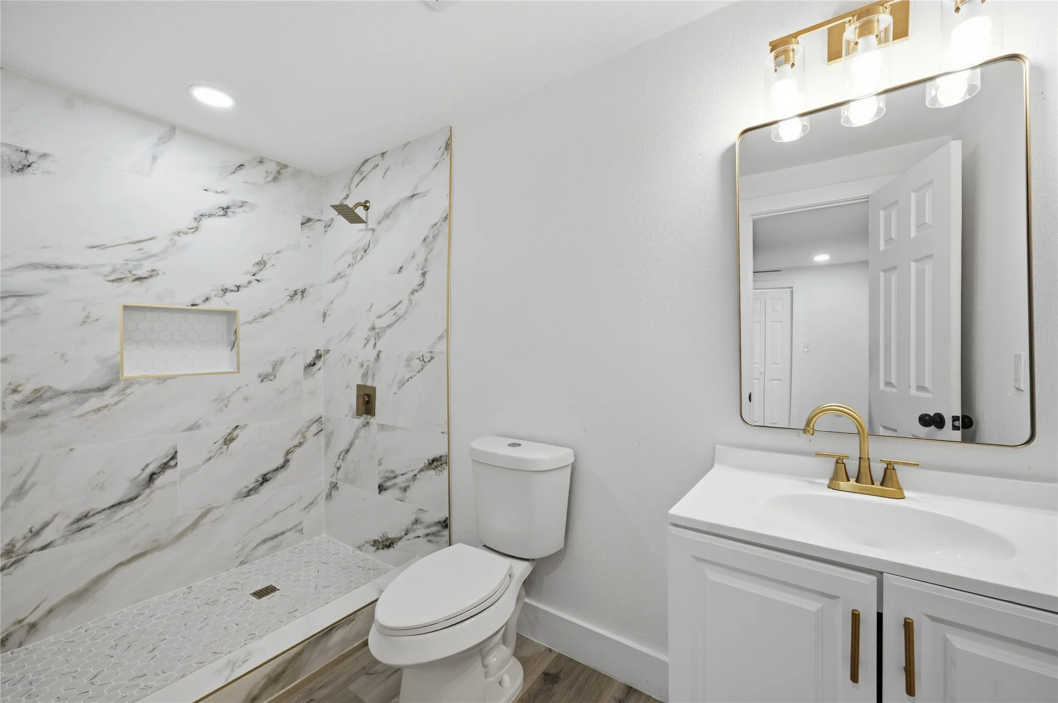 Bathroom featuring a walk-in shower with large format marble-look tiling and a recessed niche