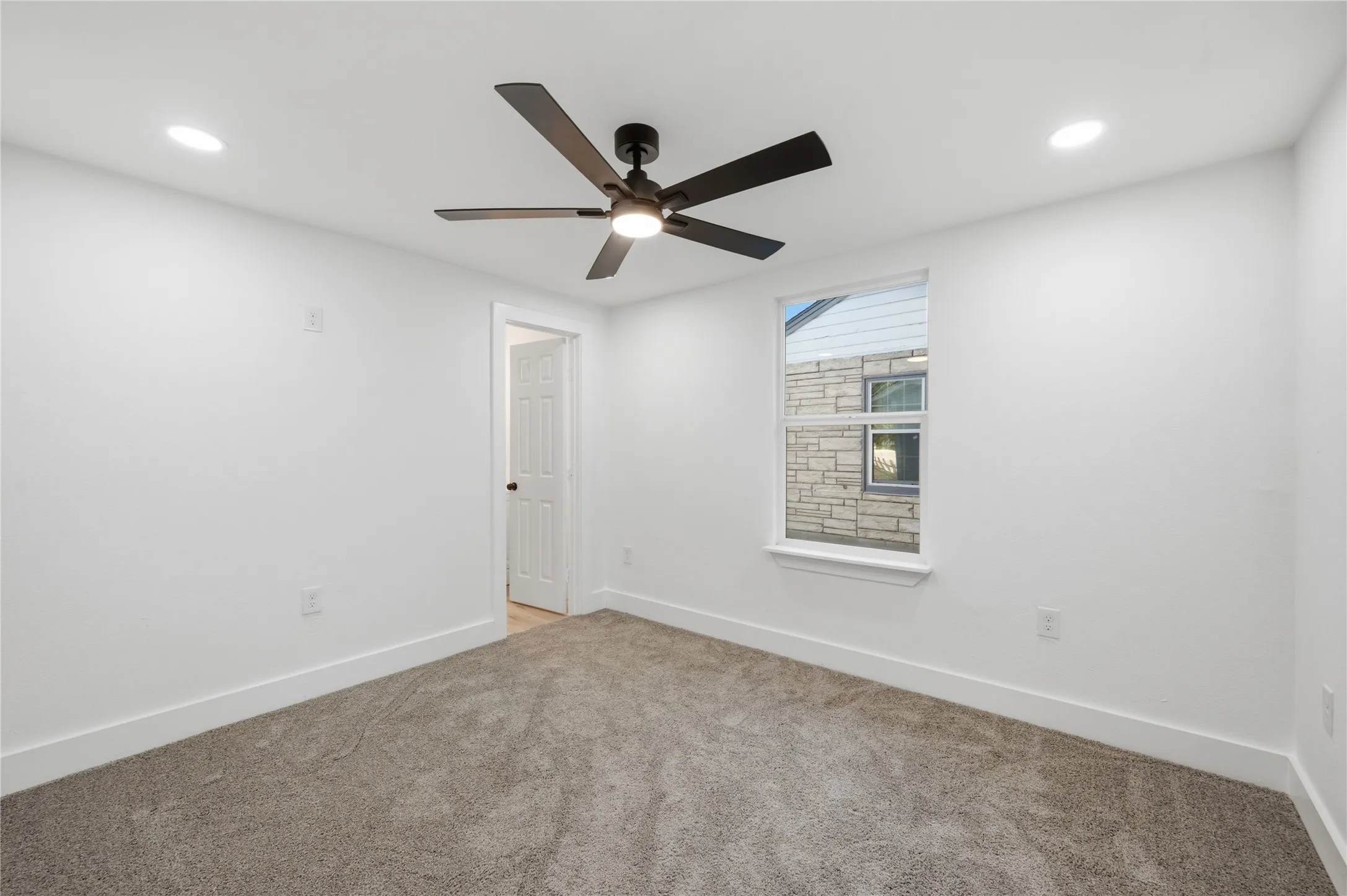 Recessed lighting, ceiling fan with integrated light, white walls, gray carpet, and white trim