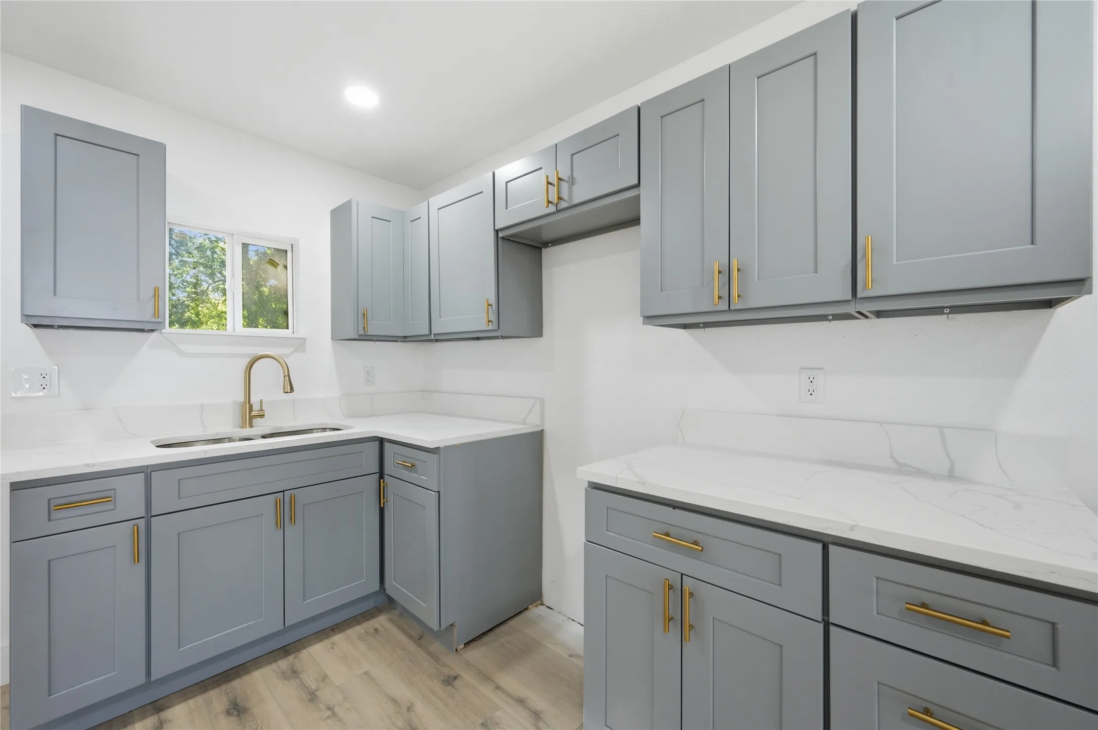 Kitchen featuring light gray cabinetry with gold hardware, white countertops, wood-finish flooring, and recessed lighting