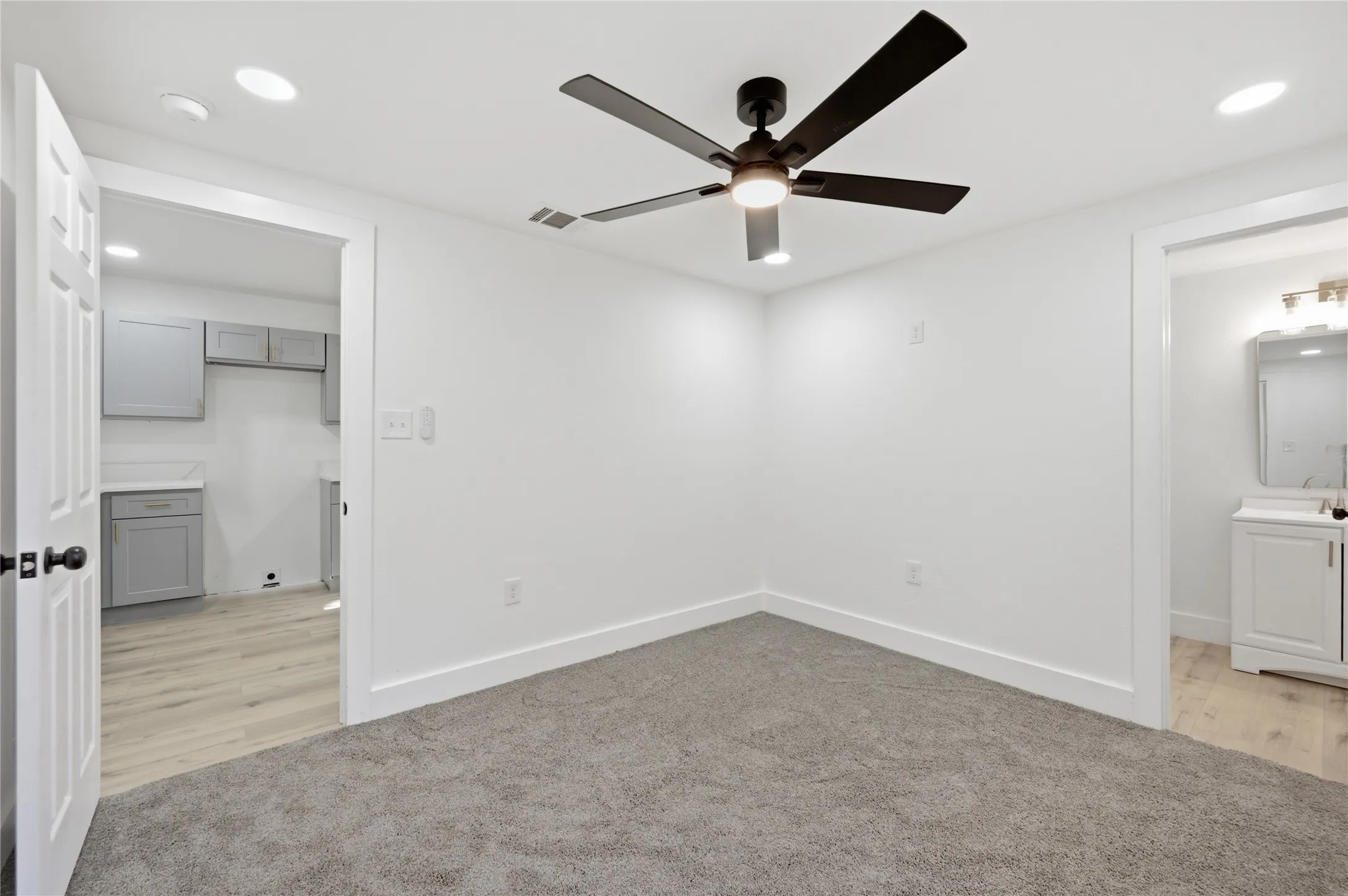 Neutral gray carpeted room with a ceiling fan, recessed lighting, and white baseboards