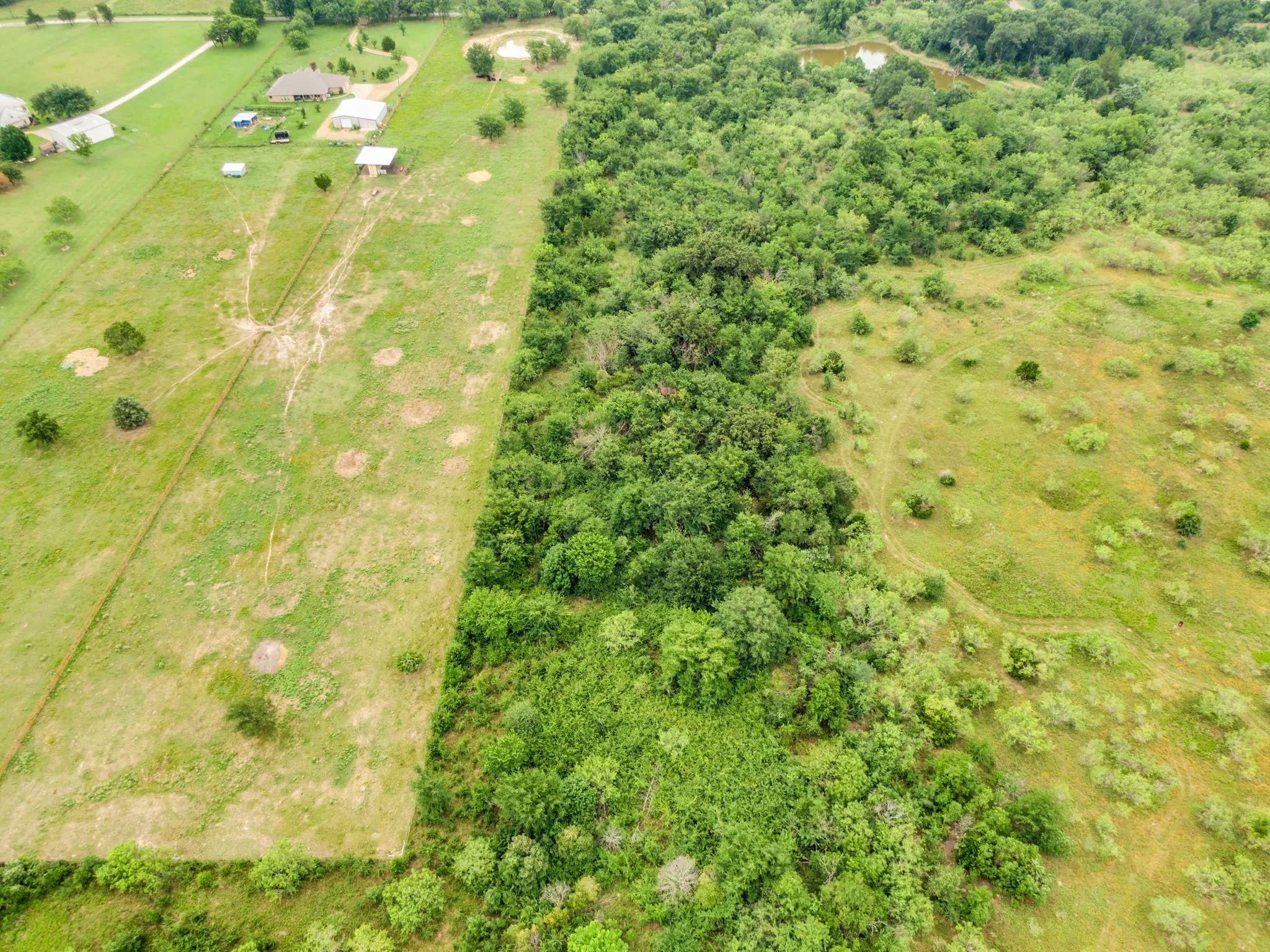 Expansive land parcel featuring a mix of open grassy areas and dense mature tree coverage