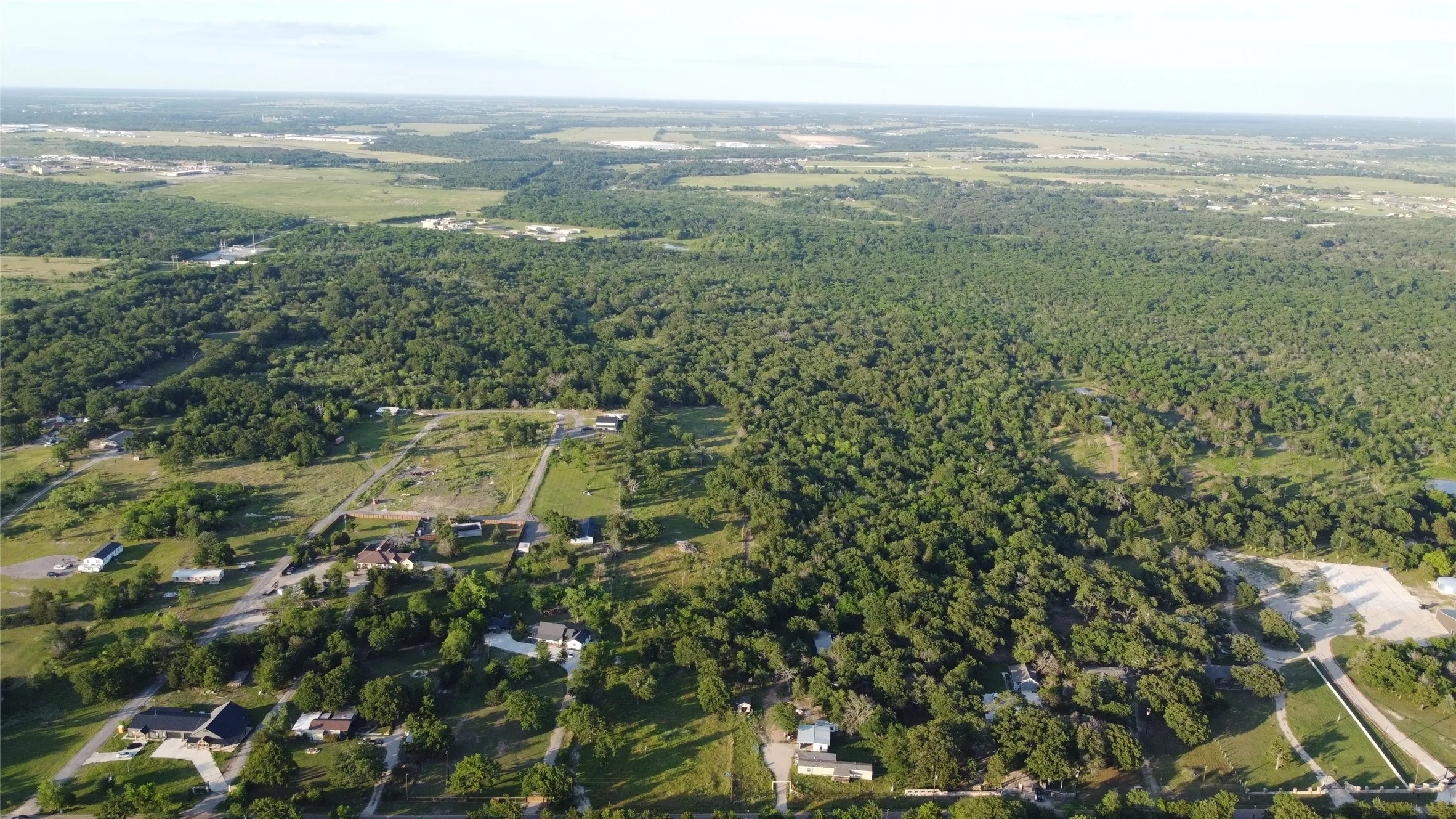 Expansive aerial perspective showcasing a verdant landscape with significant tree coverage and open clearings