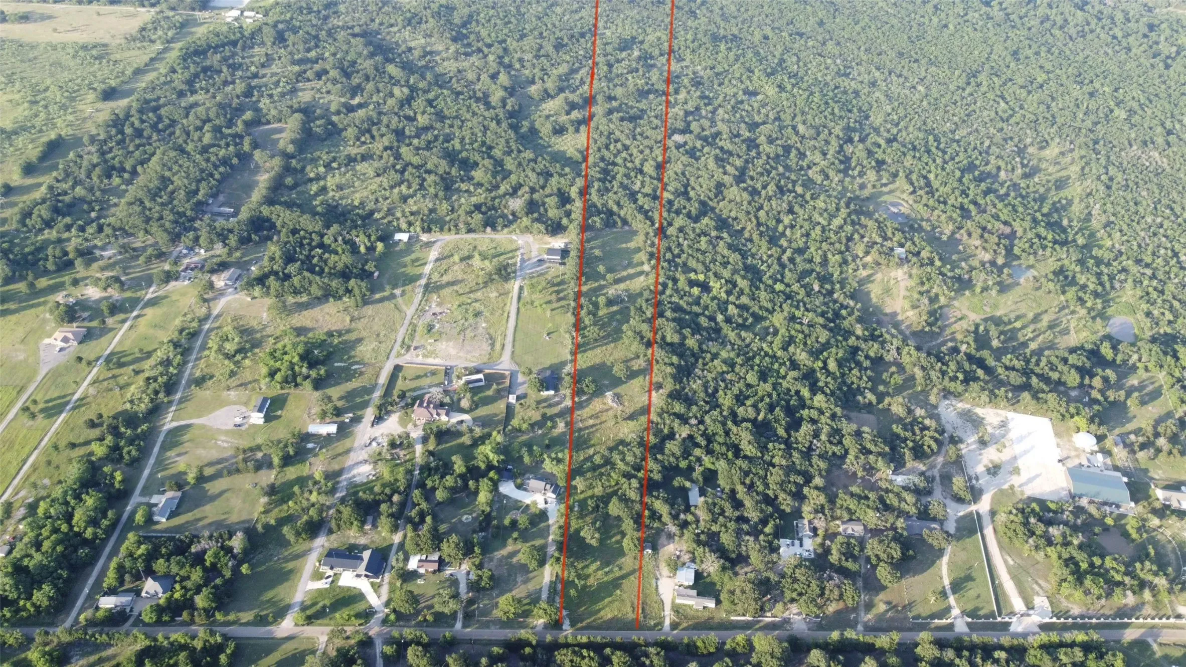 Aerial perspective of extensive land featuring a mix of cleared areas and dense tree coverage