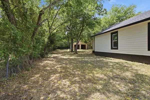 Expansive yard space featuring mature trees and a chain-link fence