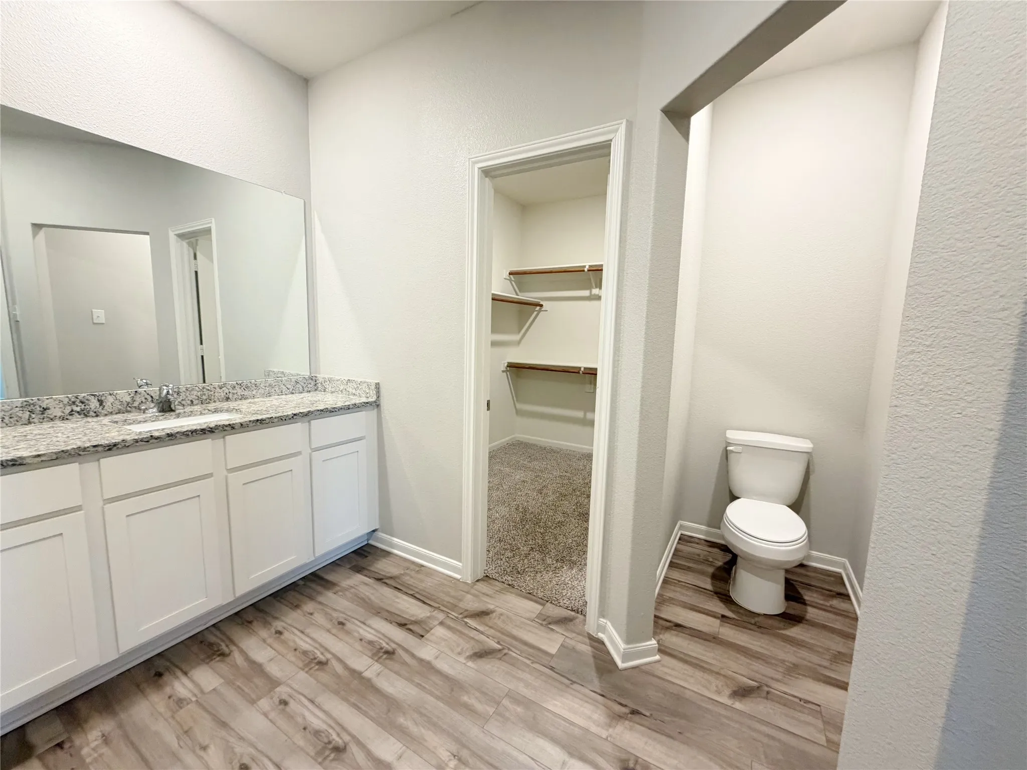 Bathroom featuring a long vanity with white cabinetry, a light-toned countertop, and a large wall-mounted mirror