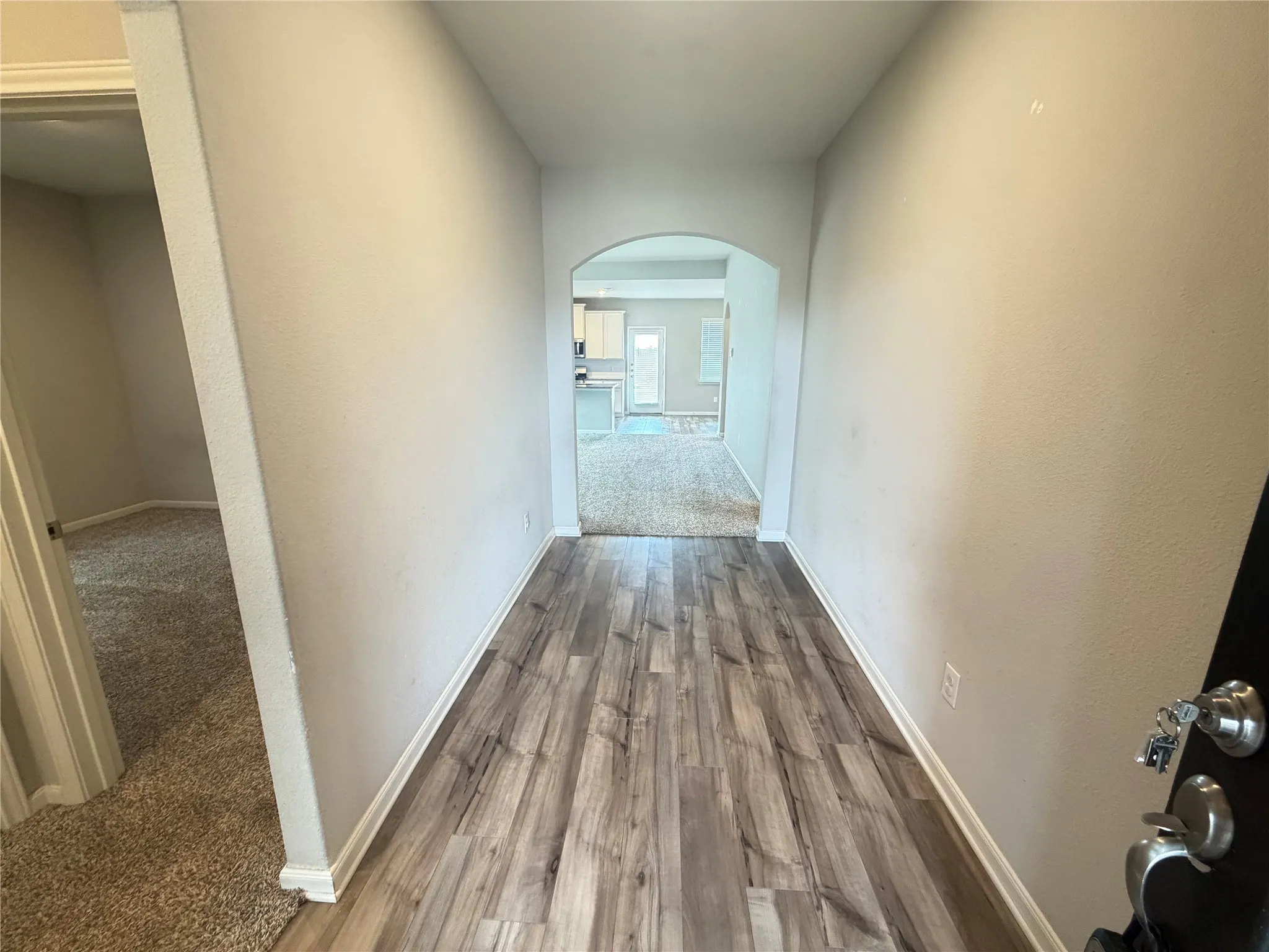 Entryway featuring wood-finish flooring, light neutral wall paint, and white baseboards
