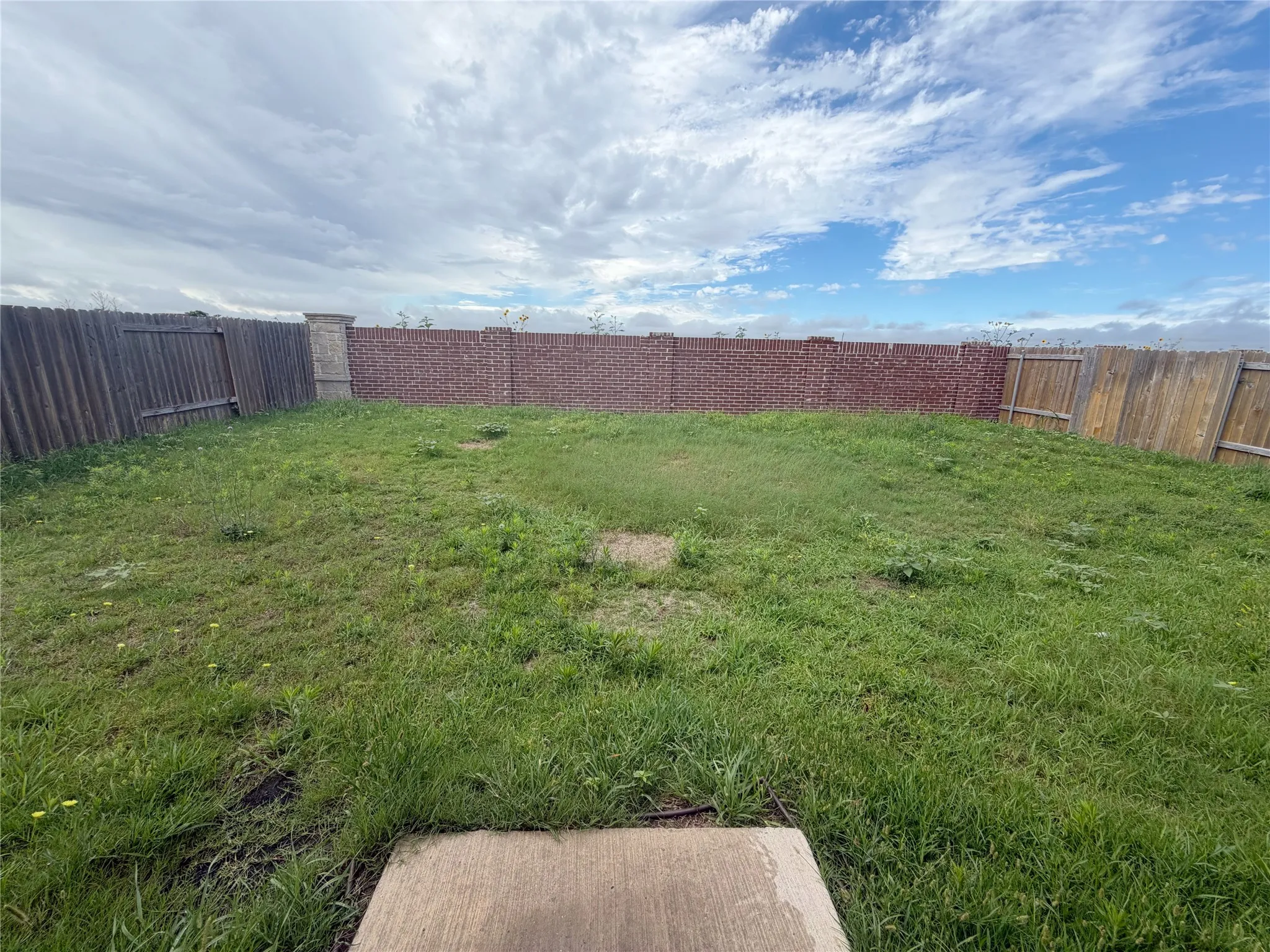 Expansive backyard featuring a combination of brick and wood fencing