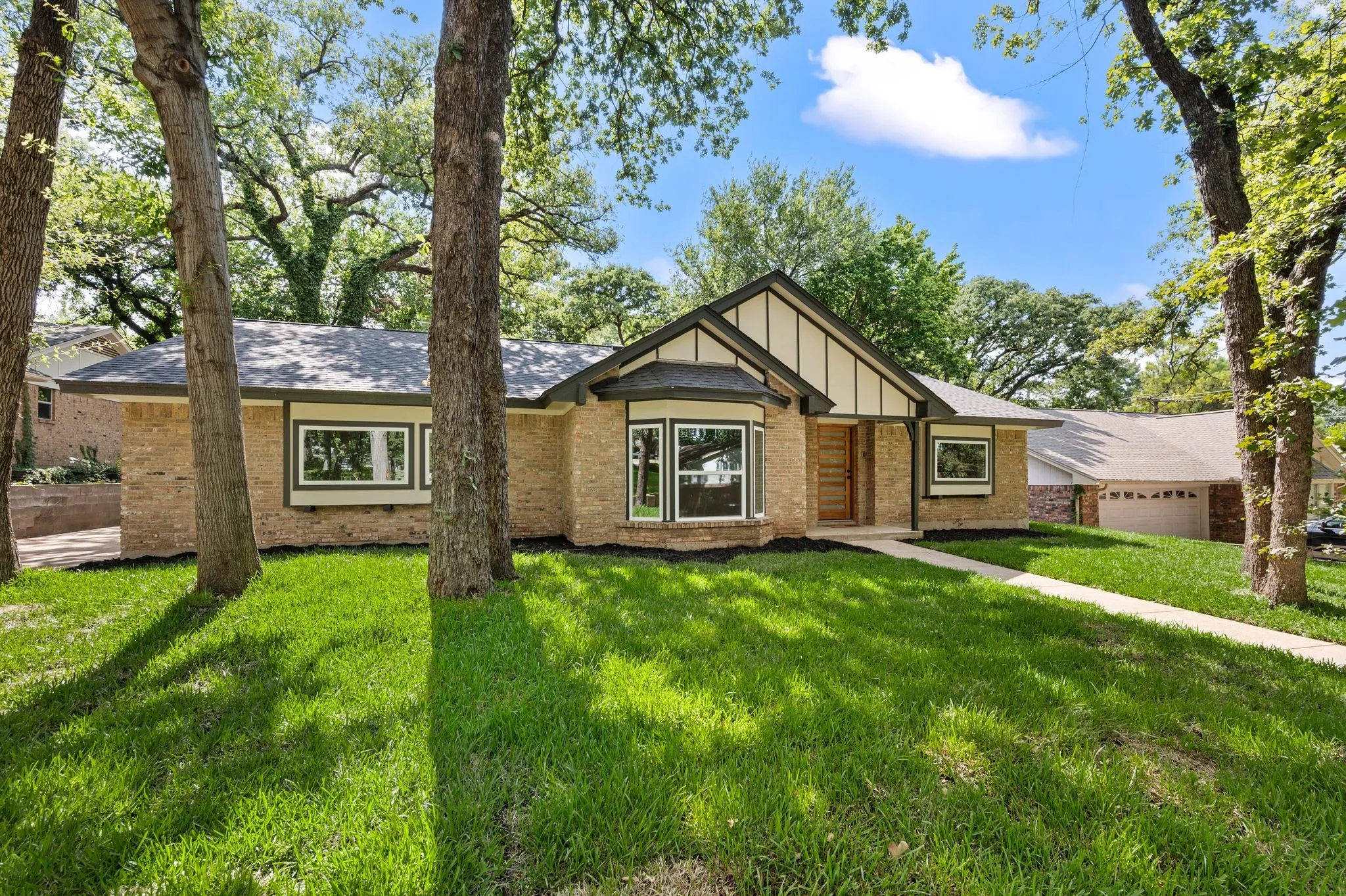 Fresh landscaping, established trees, and preserved brick character give the home a timeless presence from every angle.