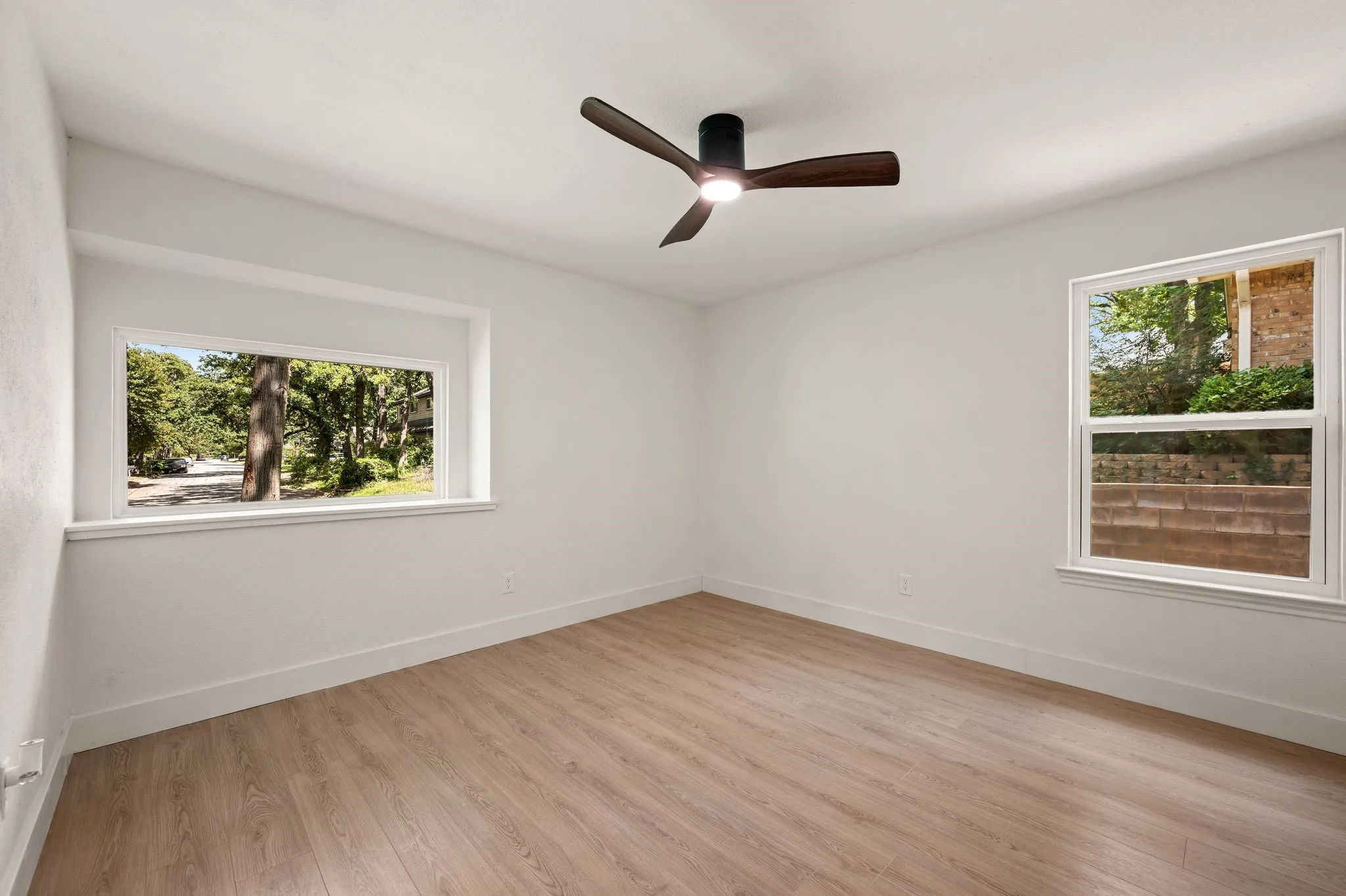 Two large windows fill this secondary bedroom with natural light and leafy neighborhood views.
