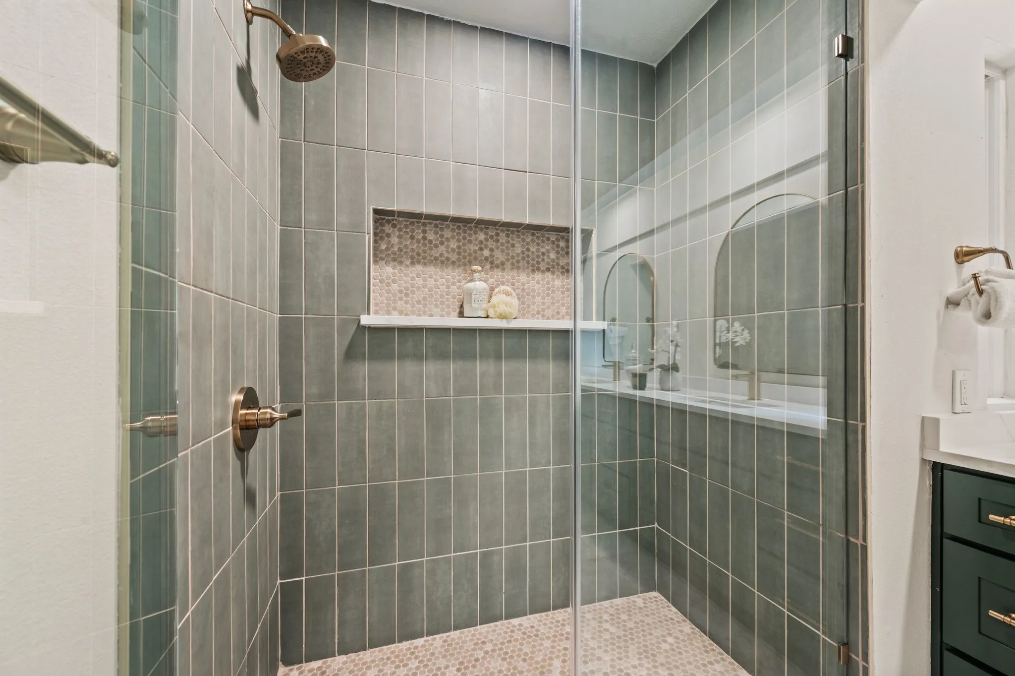 Floor-to-ceiling sage tile and a detailed shower niche bring a spa-like sense of calm to the primary suite.