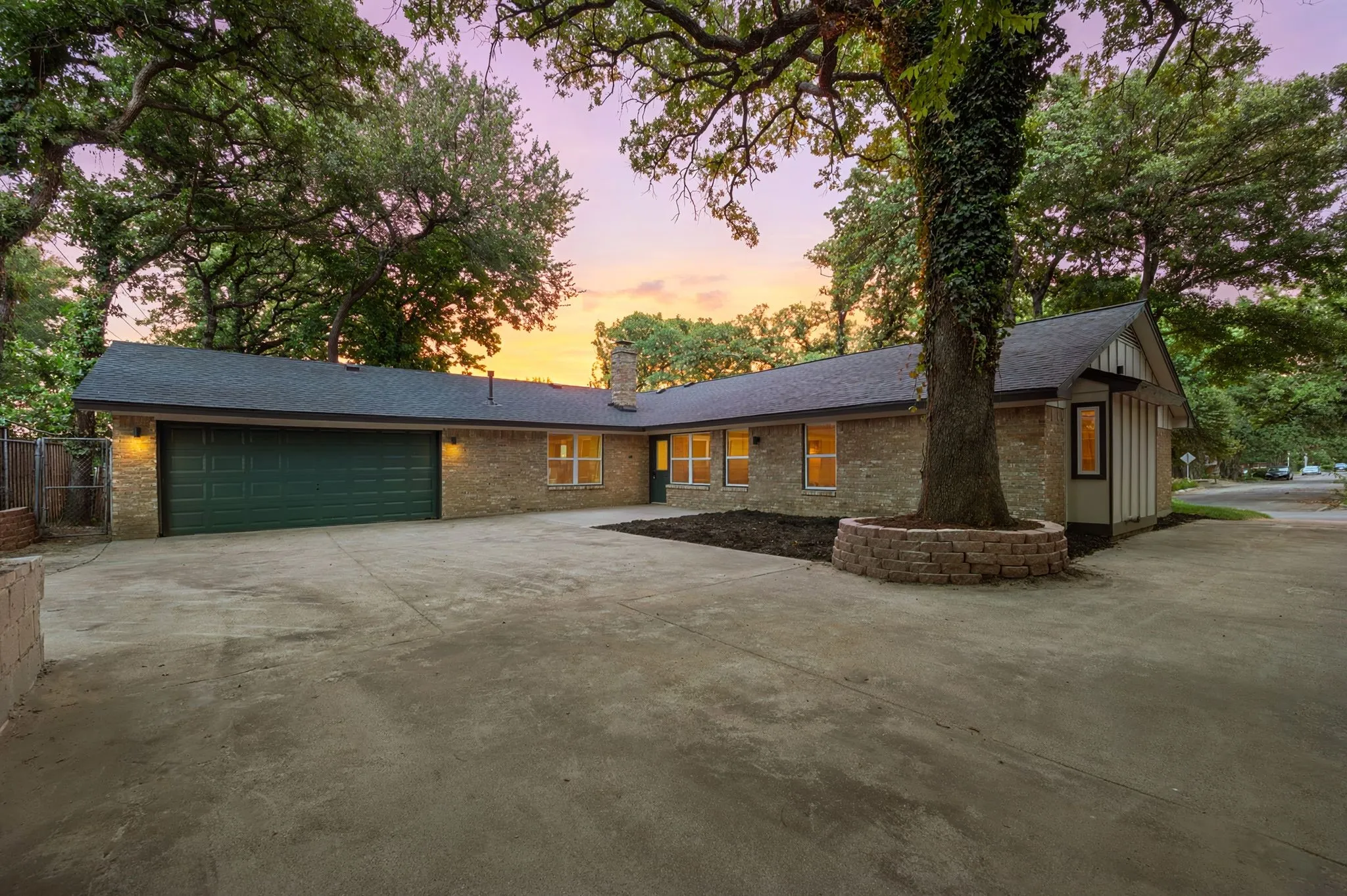 The private rear approach offers abundant paved space beneath a canopy of mature trees.