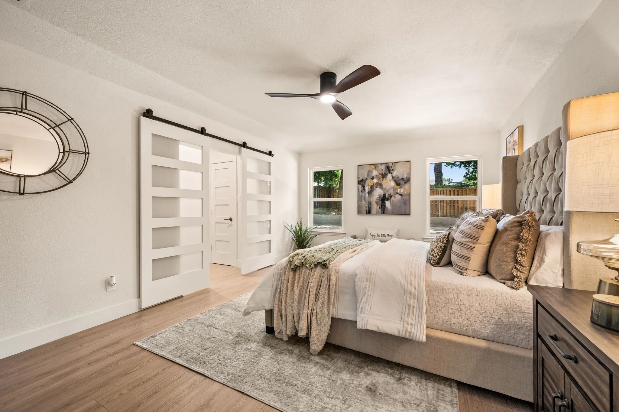 The spacious primary suite feels calm and private, with modern barn doors concealing the adjoining bath and closet area.