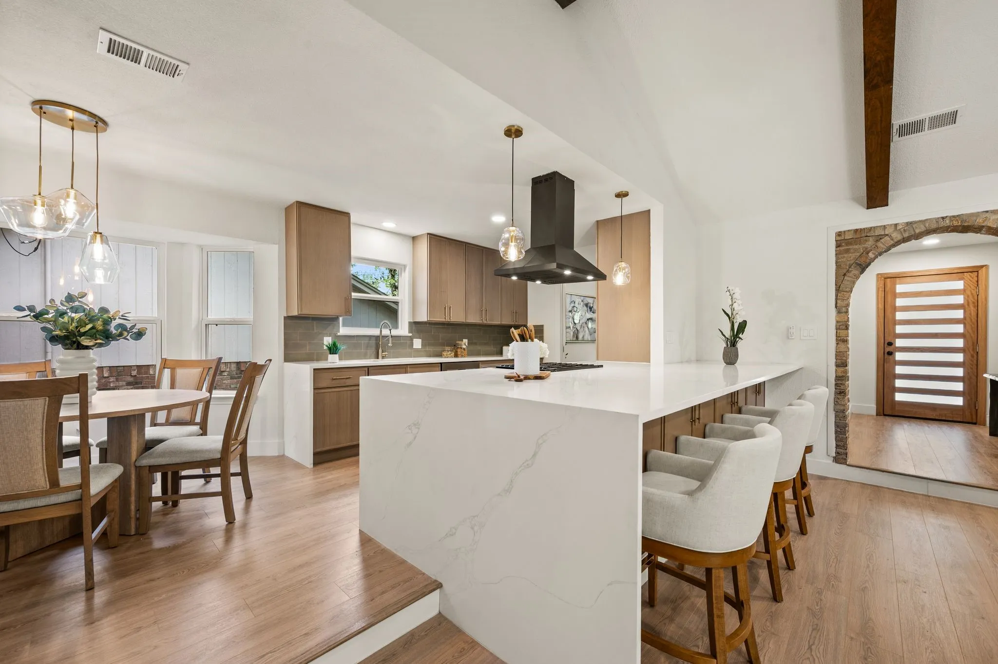 A dramatic waterfall island, generous bar seating, and warm oak cabinetry make this kitchen the natural gathering place.