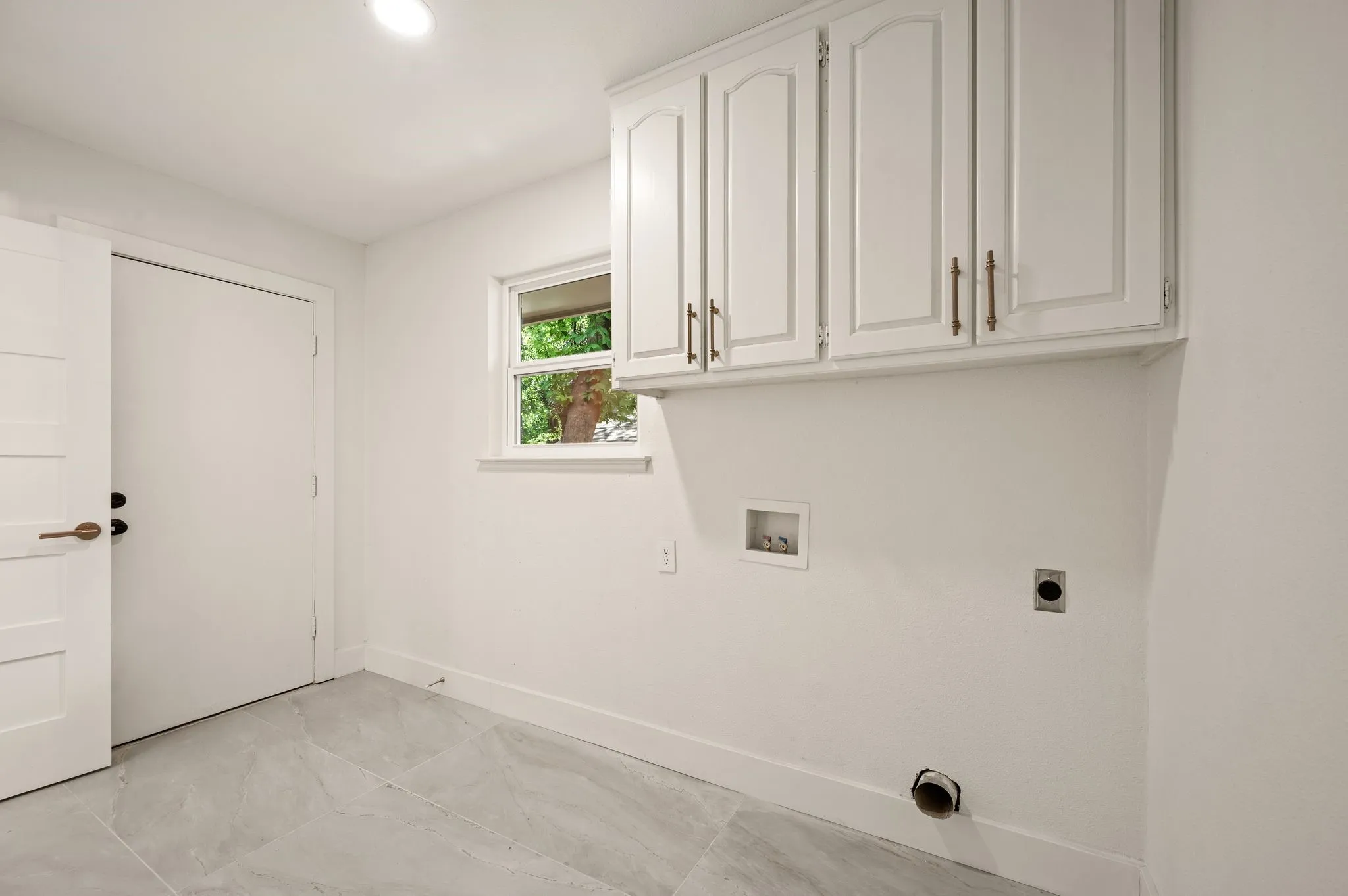 The dedicated laundry room offers upper storage, natural light, and enough space to keep daily routines organized.