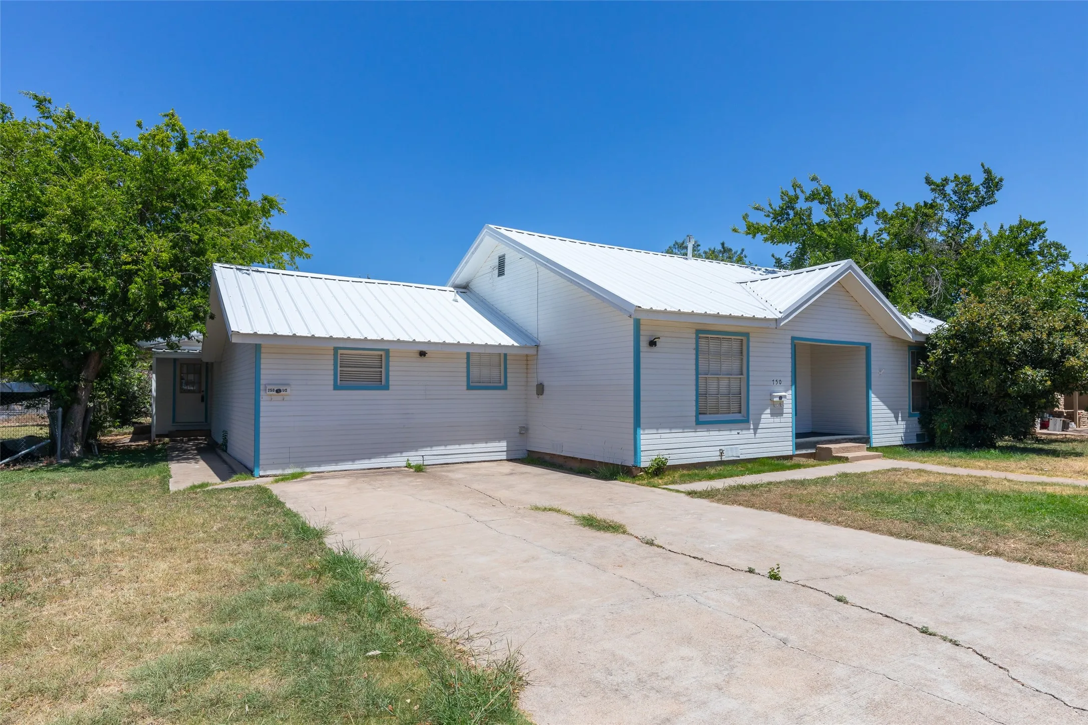 Single-story home featuring a white exterior with blue trim accents and a white metal roof