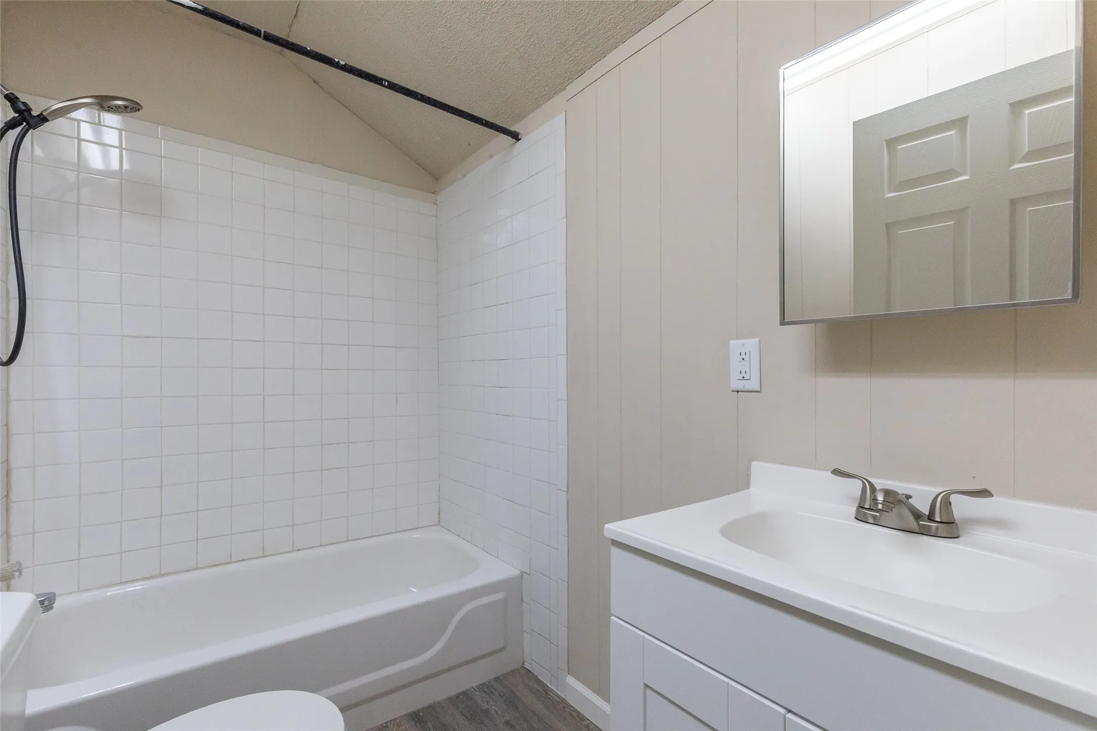 Bathroom featuring a white subway tile shower surround, a white tub, a white vanity with integrated sink, brushed nickel faucet, and a wall-mounted medicine cabinet with integrated lighting