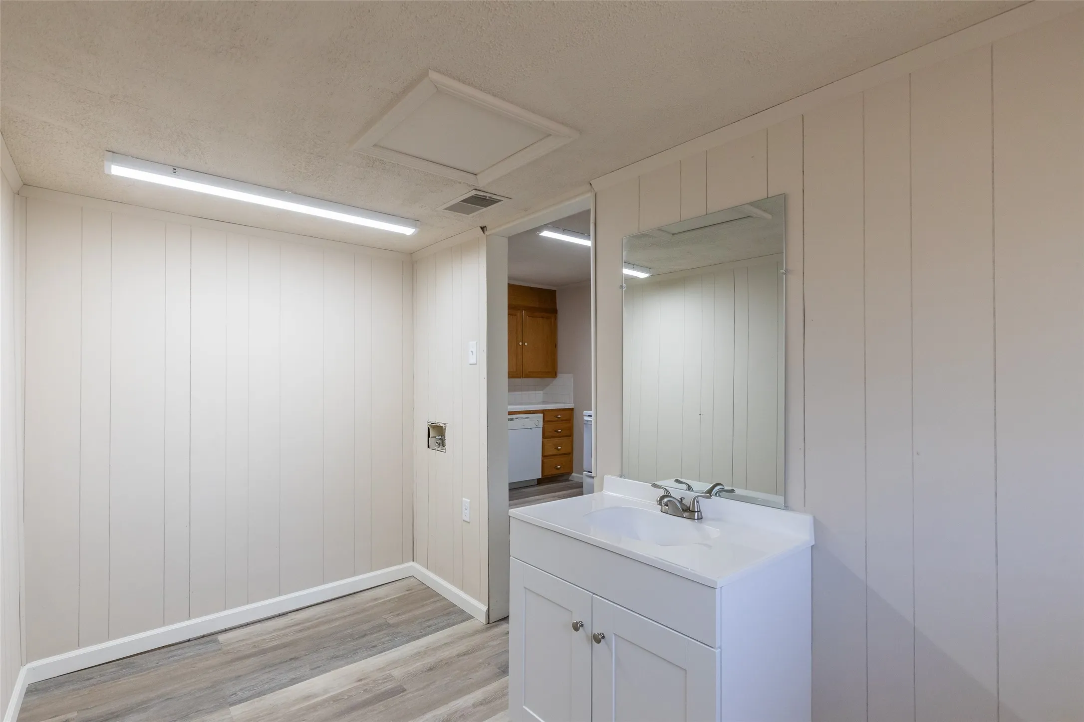 Utility room featuring a white vanity with integrated sink, chrome faucet, and mirrored backsplash